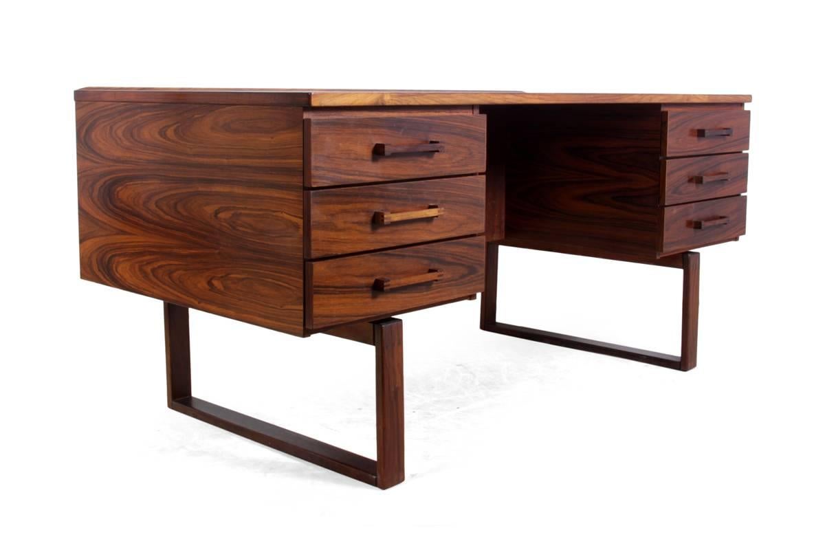 Mid-Century desk by Henning Jensen, circa 1960.
This Mid-Century, rosewood desk by Henning Jensen was made in the 1960s in Denmark. It has finger jointed handles and frame, with six drawers and a bookshelf on the back. It has a few minor age