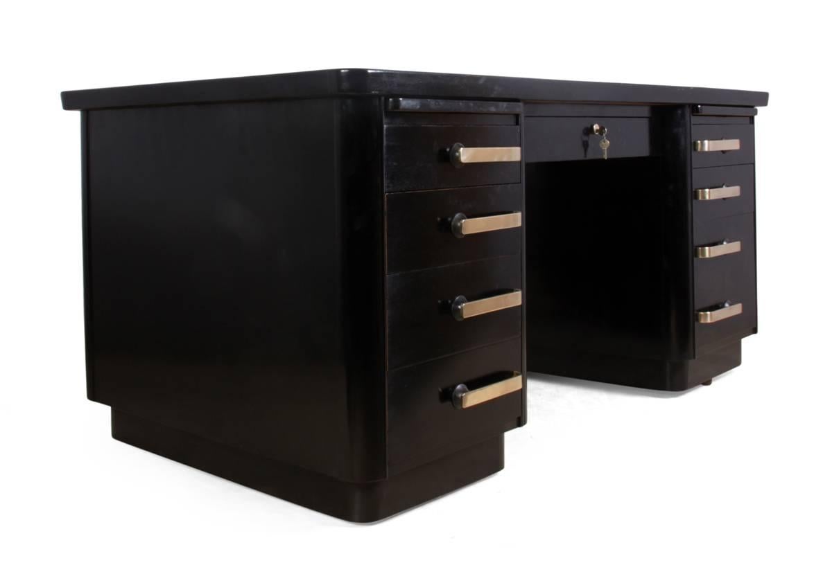 Art Deco black desk, British, circa 1950
This ebonized, Art Deco desk was produced in or circa 1950s. It has sculptural brass handles, eight drawers with the lower right being a double filing drawer, these all lock with central drawer mechanism,