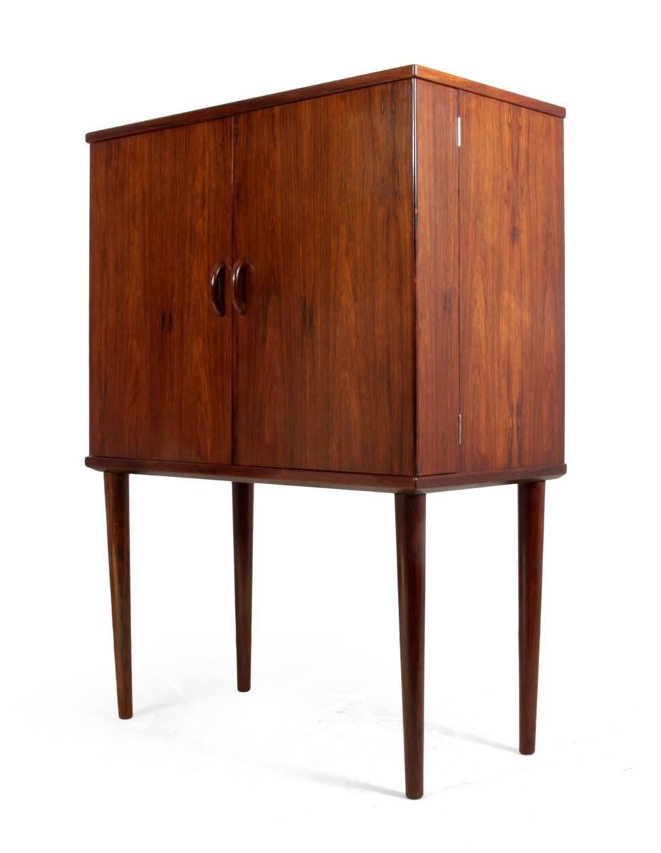 Mid-Century Danish rosewood cocktail cabinet
This Mid-Century, rosewood, cocktail cabinet was produced in Denmark in the early 1960s. It has a series of fitted shelves to the back of the door for glasses and a mirrored back with drawers below an a