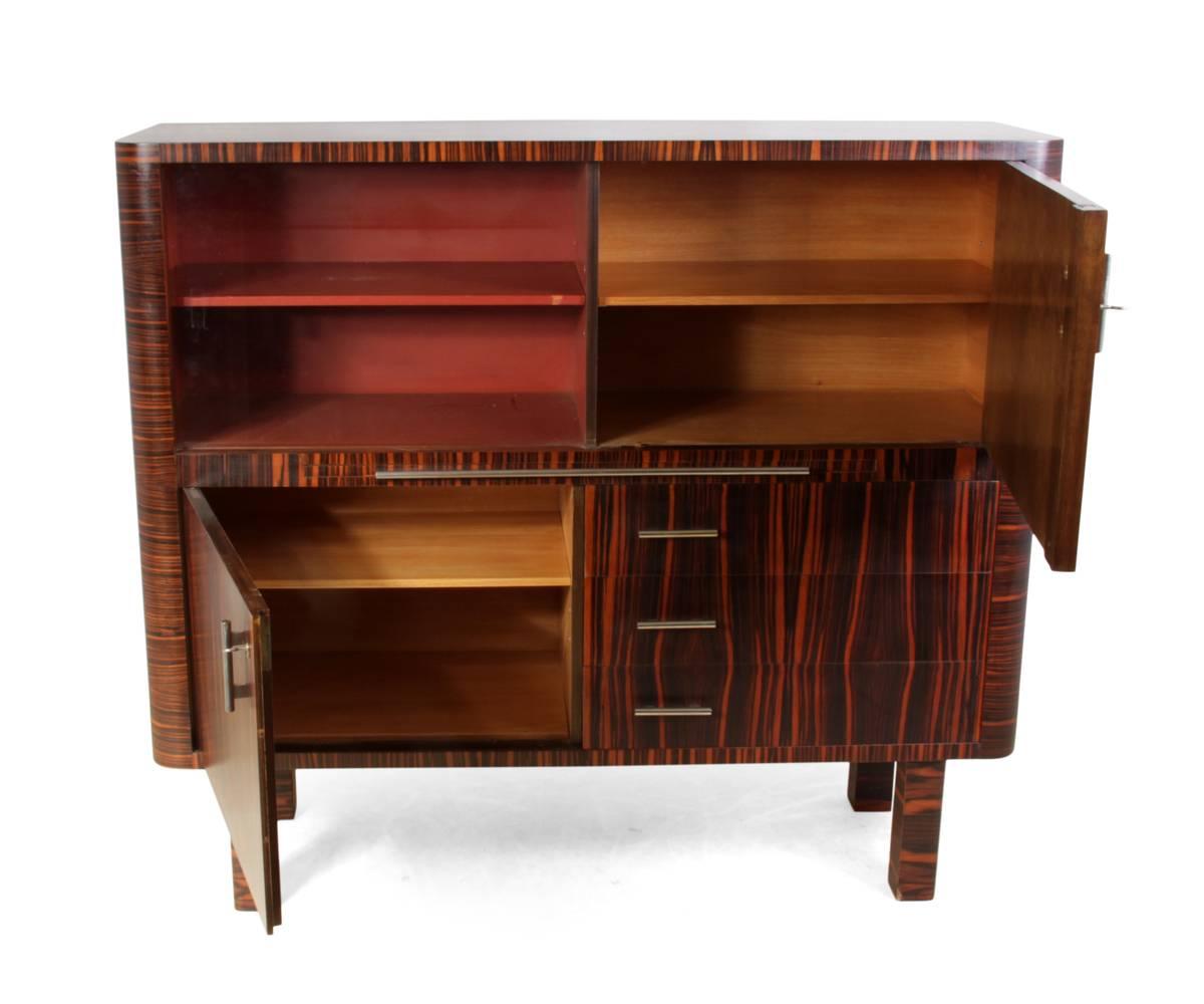 Art Deco cabinet in Macassar ebony, German, circa 1930
A German produced cabinet with Czech influence with glass sliding door to the left, lockable door to the right and below left, cocktail slide and three drawers to the lower right, this cabinet