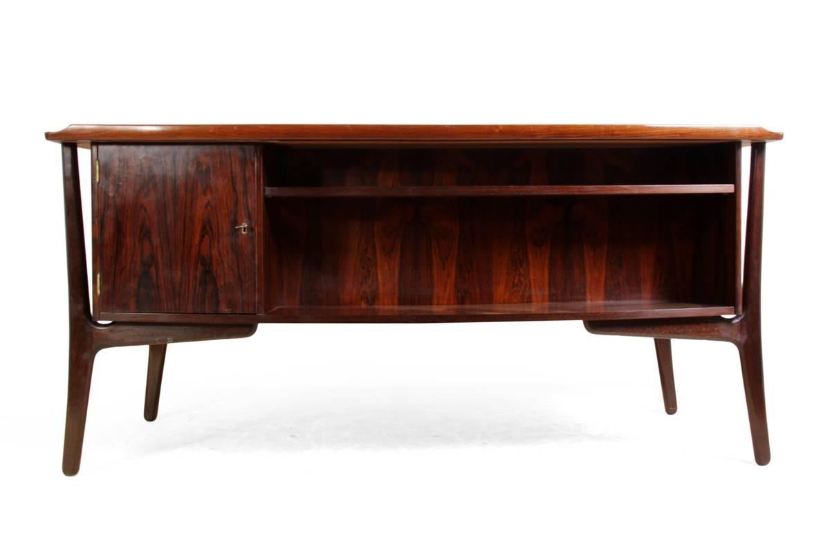 Mid Century Rosewood Desk by Svend Madsen

A rosewood desk designed by Svend Aage Madsen and produced by Sigurd Hansen in Denmark in the mid-1960s it has eight drawers with the top two lockable, to the back is a book shelf and cupboard door to the