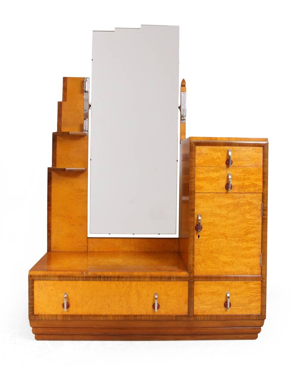 Art Deco dressing table and stool in Karelian birch, circa 1930

This dressing table was produced in the 1930s by English manufacturer, using Karelian birch, birds eye maple and walnut it has
asymmetrical design with chromed handles and lockable