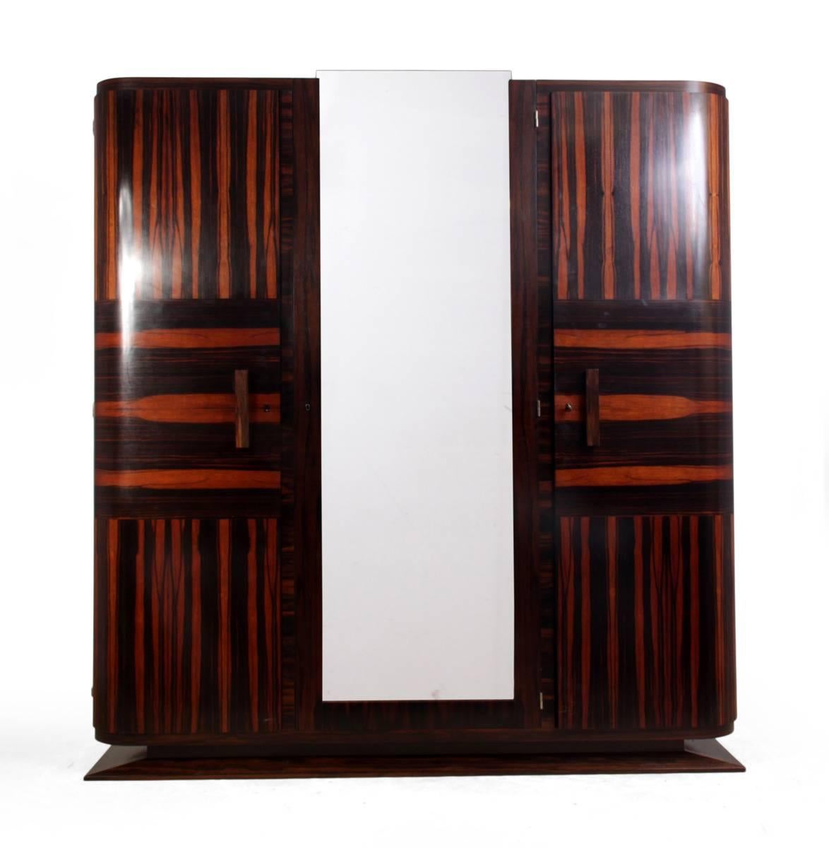 Art Deco armoire in Macassar ebony
A very rare Macassar ebony armoire, with three doors the centre door being mirrored, the two outer doors have rounded corners the original key supplied fits all three doors, the shelves behind are fully adjustable