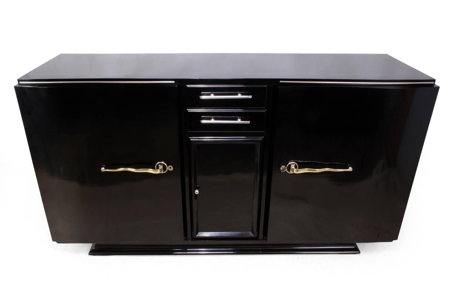Art Deco black piano lacquer sideboard, circa 1930
This sideboard has two central drawers with a cupboard below and two large shaped doors either side, it has brass and chrome fitting with one key that locks the two large doors, the sideboard has