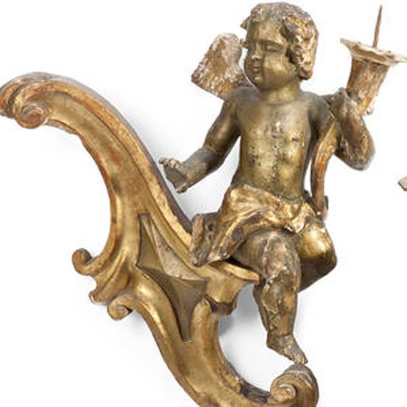 18th century Italian pair of Rococo giltwood and silvered sconces with carved angel holding a pricket stick and leaning on a reverse scroll.