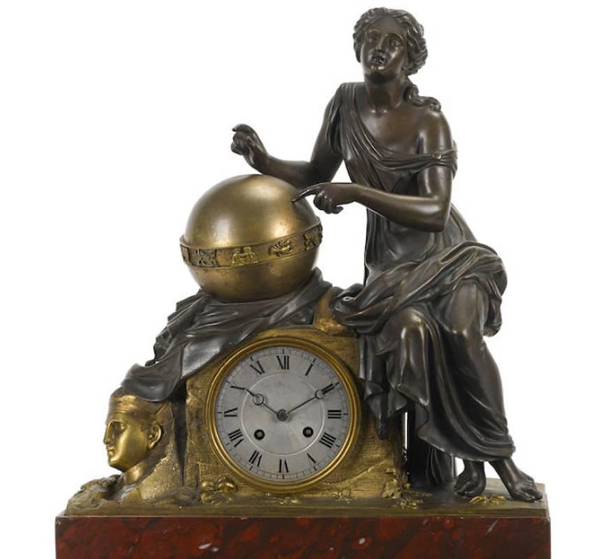 19th century French Empire style gilt and patinated bronze figural mantel clock. The Classical seated maiden above Roman numeral dial leaning on gilt bronze orb next to Sphinx head, all on Royal Rouge marble plinth.