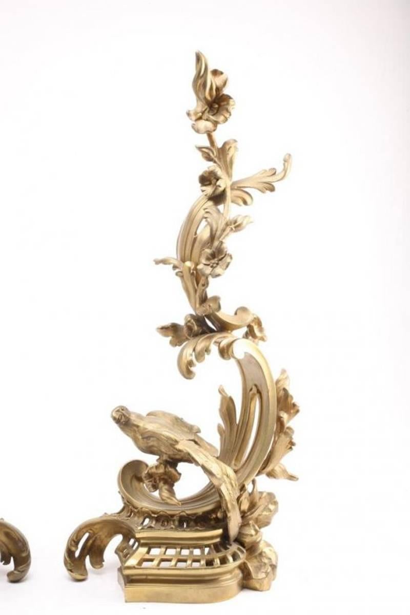This unique 19th century pair of French gilt bronze andirons is filled with flowers and scrolled acanthus leafs centered by a fine cast bird on fretwork base. 
The birds as well as the scrolled acanthus leafs and flowers are a mirrored image of