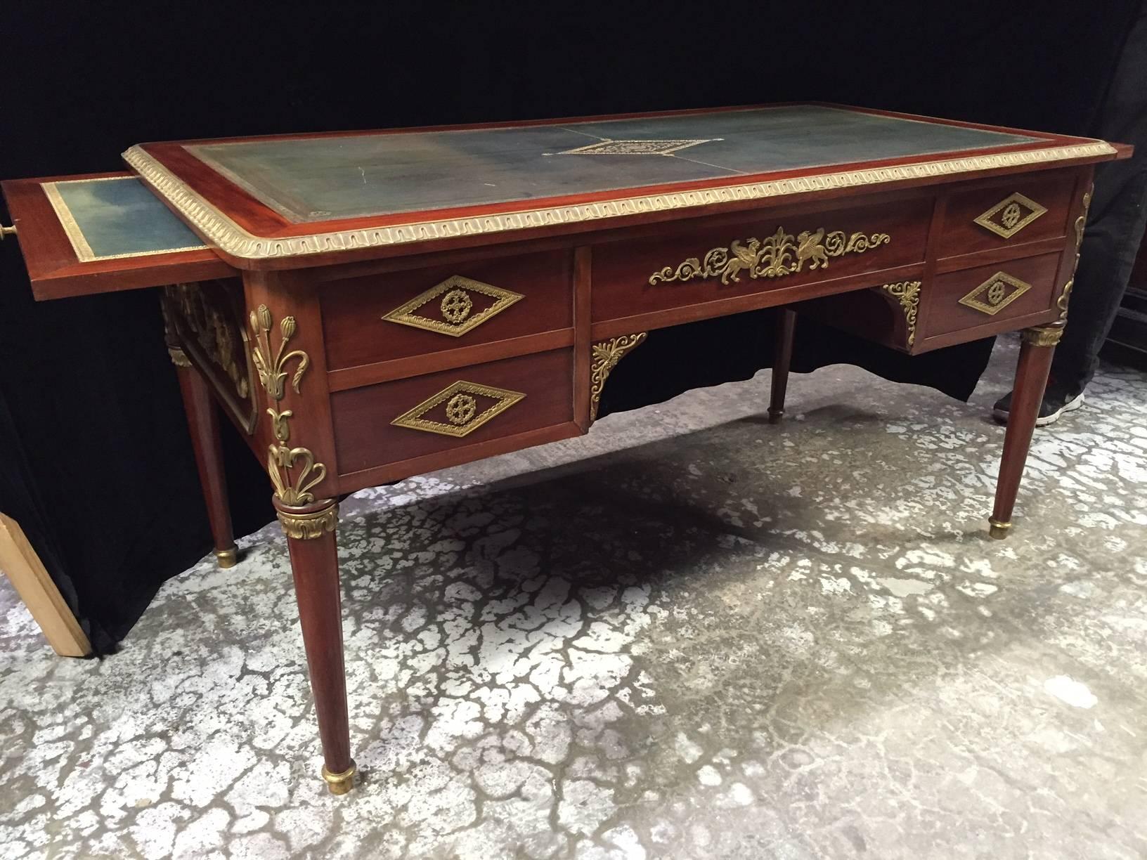 Impressive 19th century fine Empire style gilt bronze-mounted mahogany five drawer bureau plat with leather top and two side slides, on four round tapered legs. All sides with finely chased ormolu mounts. 

The two slides both extend an additional