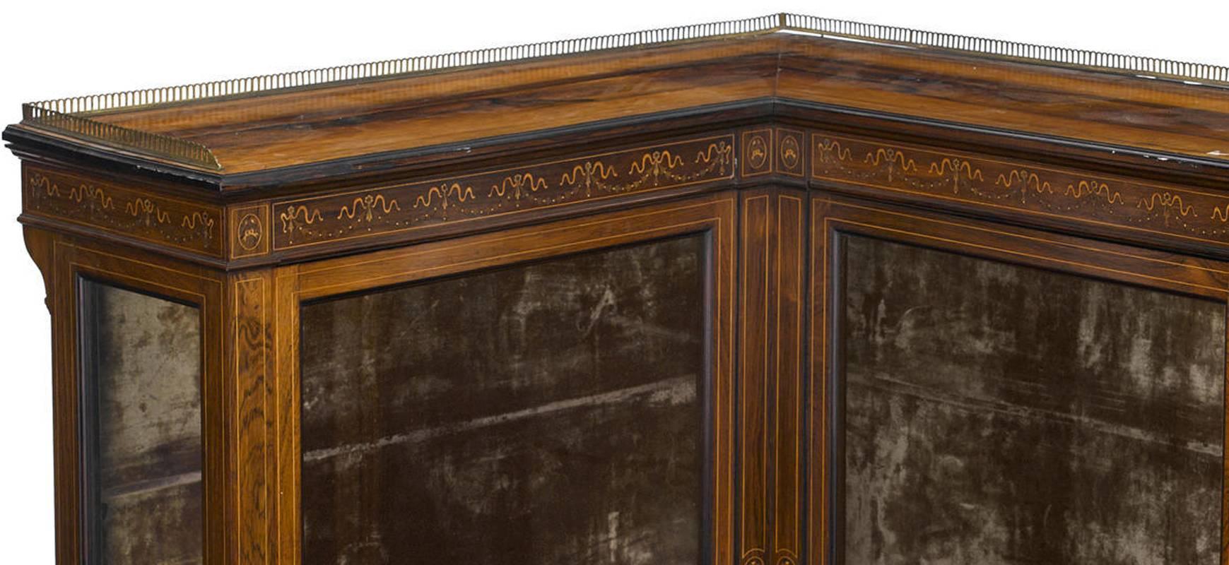 Very unusual and unique 19th century English finely inlaid rosewood corner display cabinet with velvet lining interior. Display cabinet has an open gallery on the top with detailed garland and ribbon motif inlaid above two glass swinging doors, all
