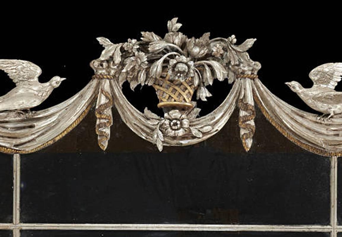 Unique Italian horizontal Baroque style silver leafed and finely carved wood over mantel mirror.
The well carved pair of birds flank a bouquet of flowers sitting on swags and drapery cornered by a pair of angel heads with wings. The sides consist