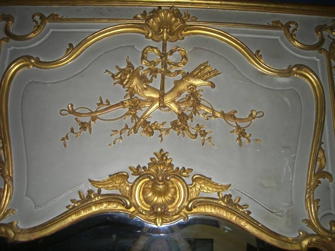 Monumentale et magnifique boiserie de miroir de style Louis XVI du 19e siècle, finement sculptée et décorée de dorure à la feuille de 23 carats et de peinture vert clair/gris, avec motif de carquois d'arc et de flèches sur le dessus.  

Il y en a un