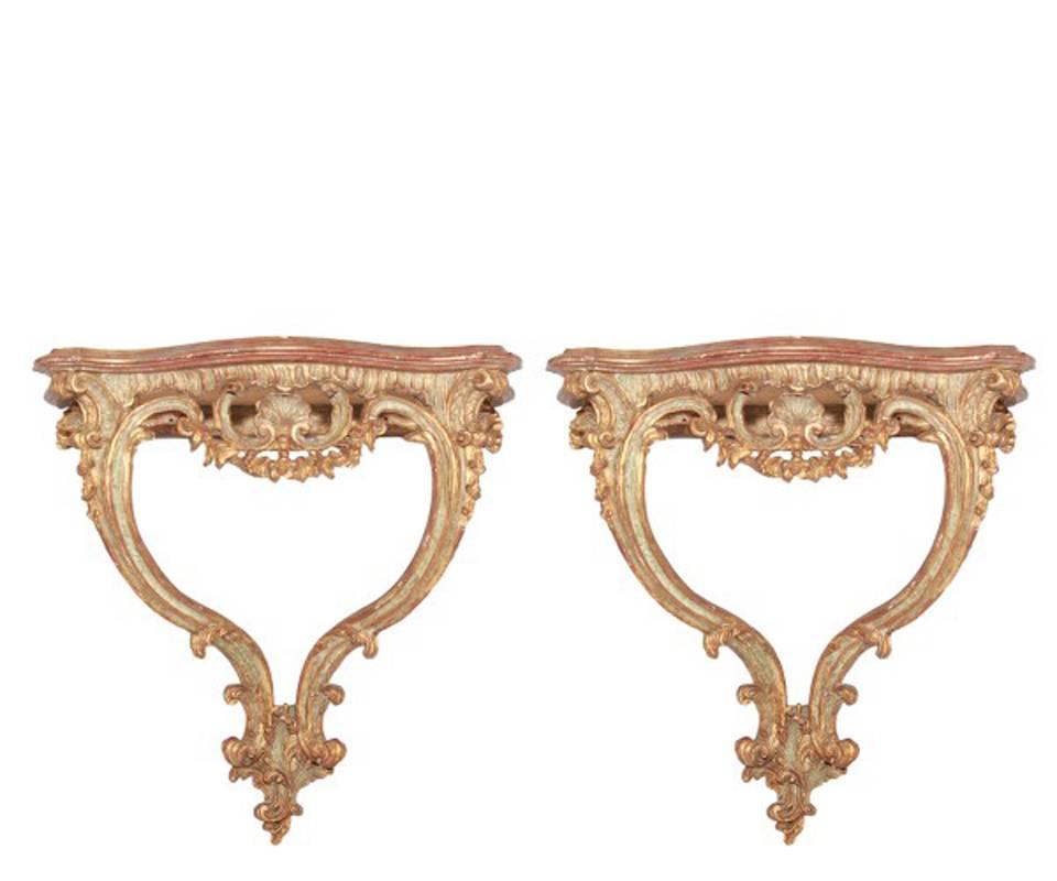 Attractive pair of small 19th century Italian Rococo style wall consoles each with red painted tops over parcel-gilt and painted scrolling and acanthus leaf motif consoles centered by shell within rocaille scrollwork and foliage, all supported by