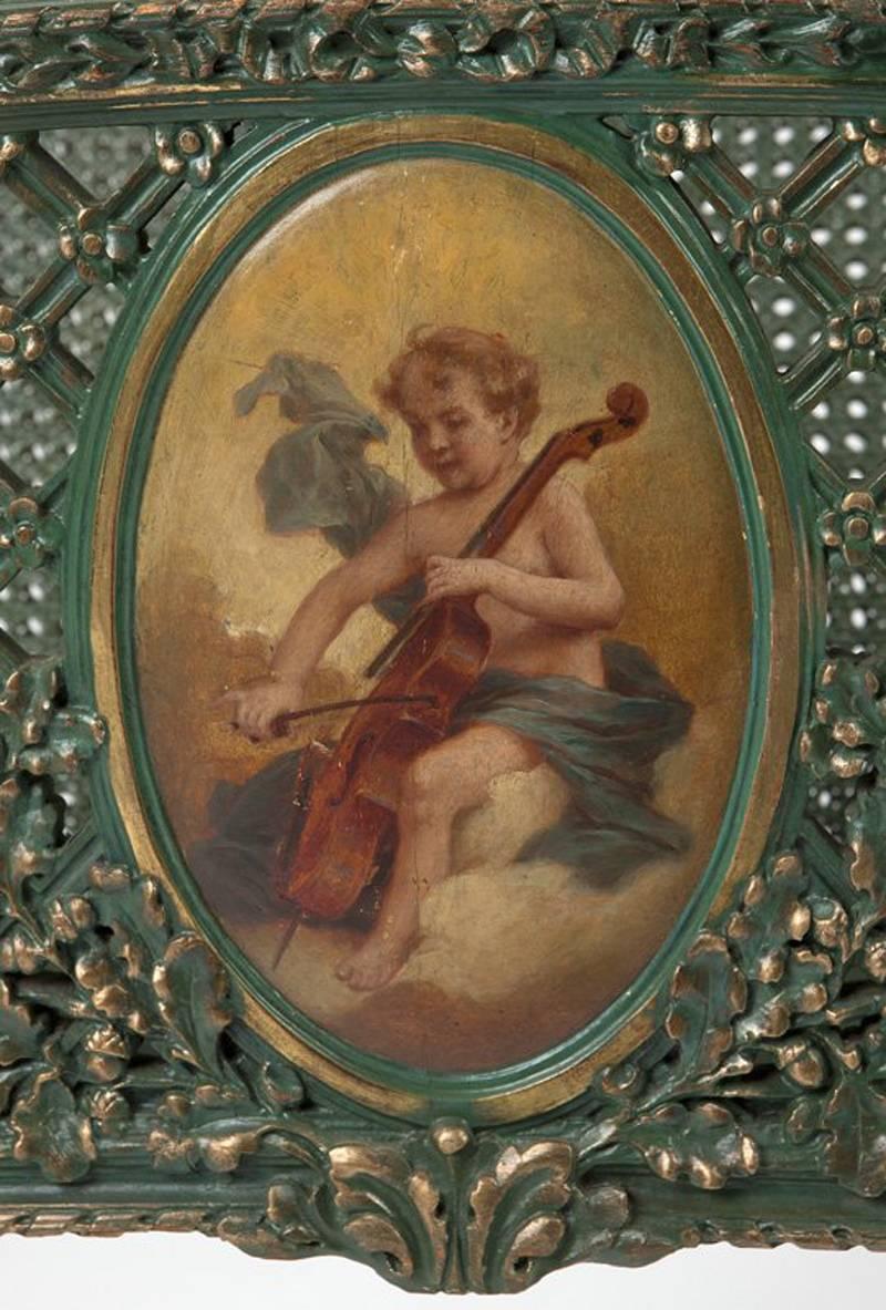 Unusual Louis XVI style green painted Canterbury, mid-20th century. Carved fretwork front centered by an oval painting of a seated cherub playing a harp and caned in the back, all on tapered receded legs.