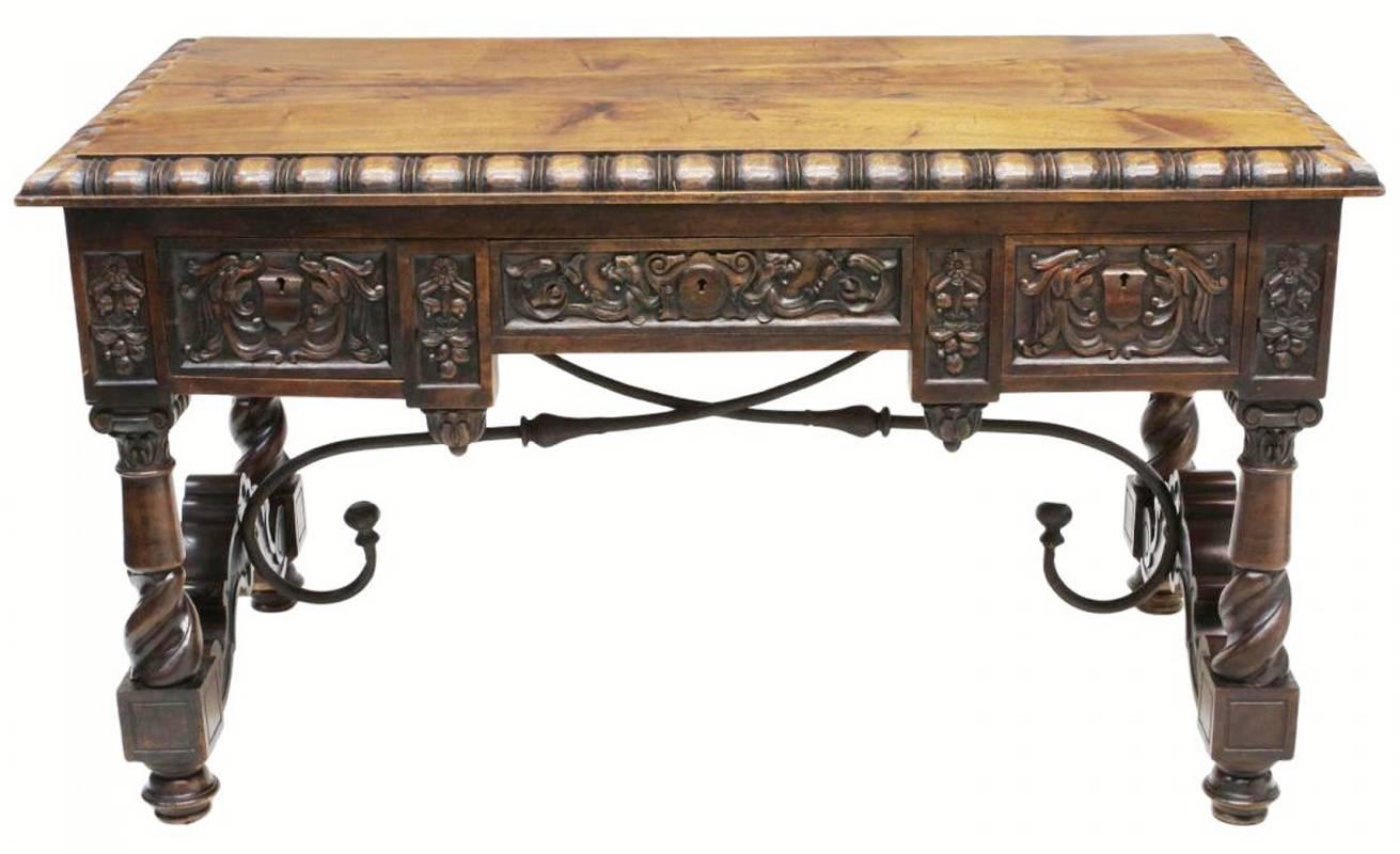 19th century Spanish Renaissance style finely carved chestnut three drawer desk on four cylindrical and spiral legs with wood and hand-forged elegantly curved iron stretchers.

 
