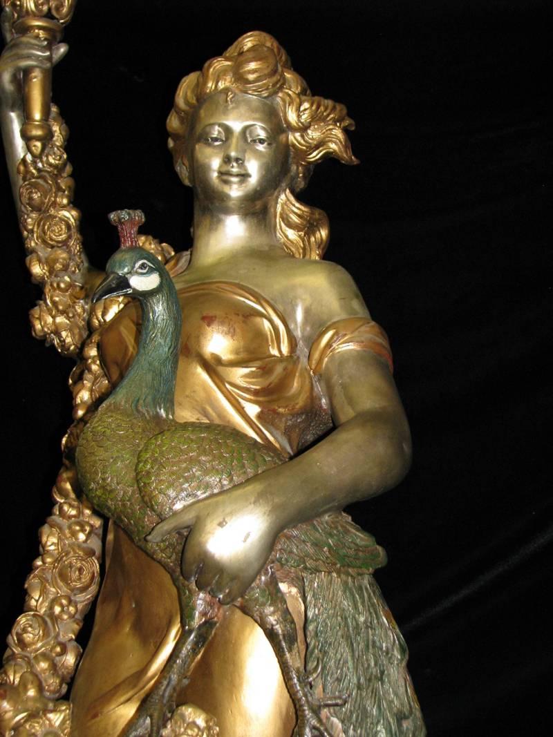 Late 20th century monumental pair of fine gilt and patinated bronze figural torchieres. 
Pair of monumental bronze tochiere lamps, gold and silver patinated bronze, depicting maidens holding male and female peacocks and glass flame globe torches