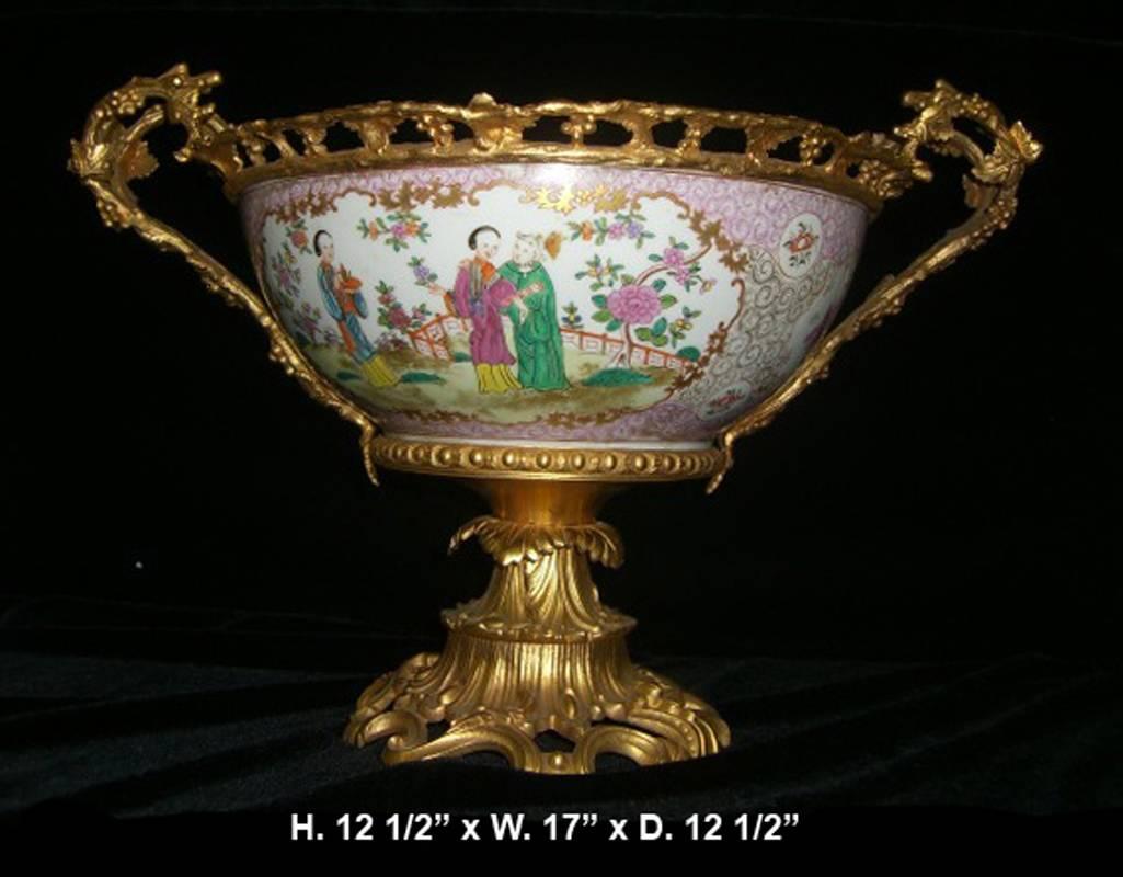 Lovely 19th century French ormolu-mounted Chinese porcelain bowl centerpiece.

Salmon colored Chinese porcelain bowl centered by two central cartouches depicting figural garden scenes, trimmed with a ormolu pierced rim, flanked by intricate