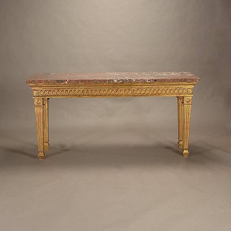 Fine Italian neoclassical style 23-karat gold leafed long and narrow console table. The thick rectangular marble top over carved giltwood frieze on four fluted and tapered square legs,

Second half of the 20th century.