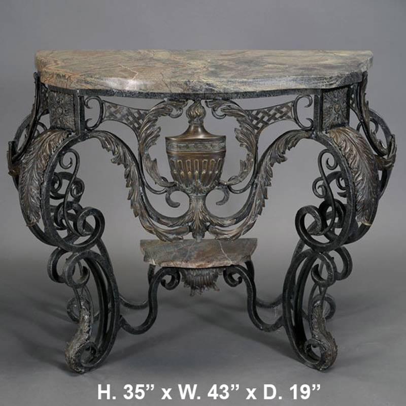 Attractive pair of continental Baroque style hand-forged wrought iron and bronze consoles with thick marble tops both consoles centered with a bronze urn encased in a foliage cartouche and supported by four double scrolled legs mounted with bronze