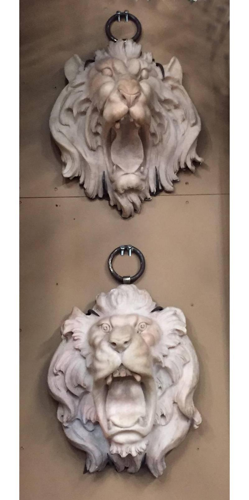 Pair of Italian finely carved marble lion heads mounted on an iron back plate and loop for the purpose of hanging.
Carved Marble Lion Heads with highly articulate mane and a lively roaring facial expressions.
These sculptures could be used as a