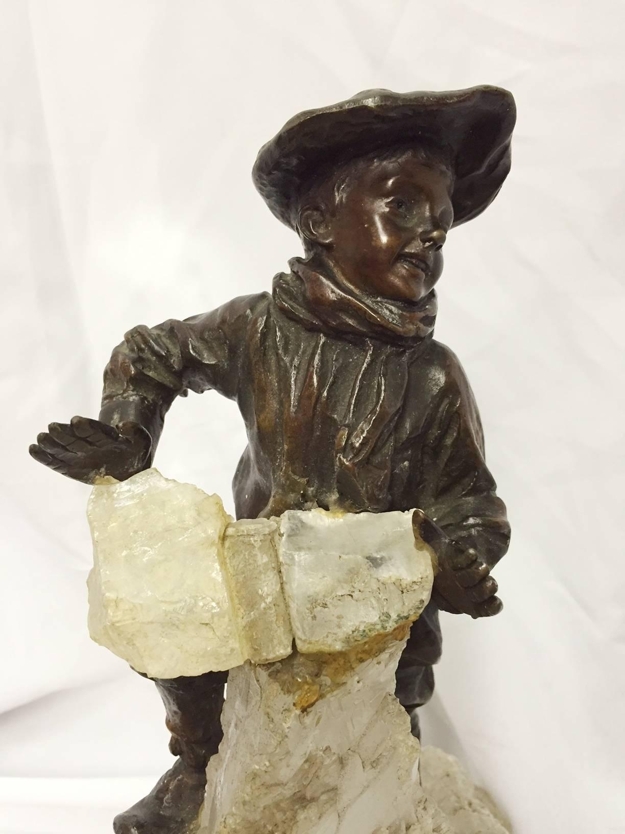Fine 19 Century French patinated metal boy climbing rock crystal mountain. The joyous Renaissance boy dressed in Bourgeois garments and hat climbing natural rough rock crystal mountain.