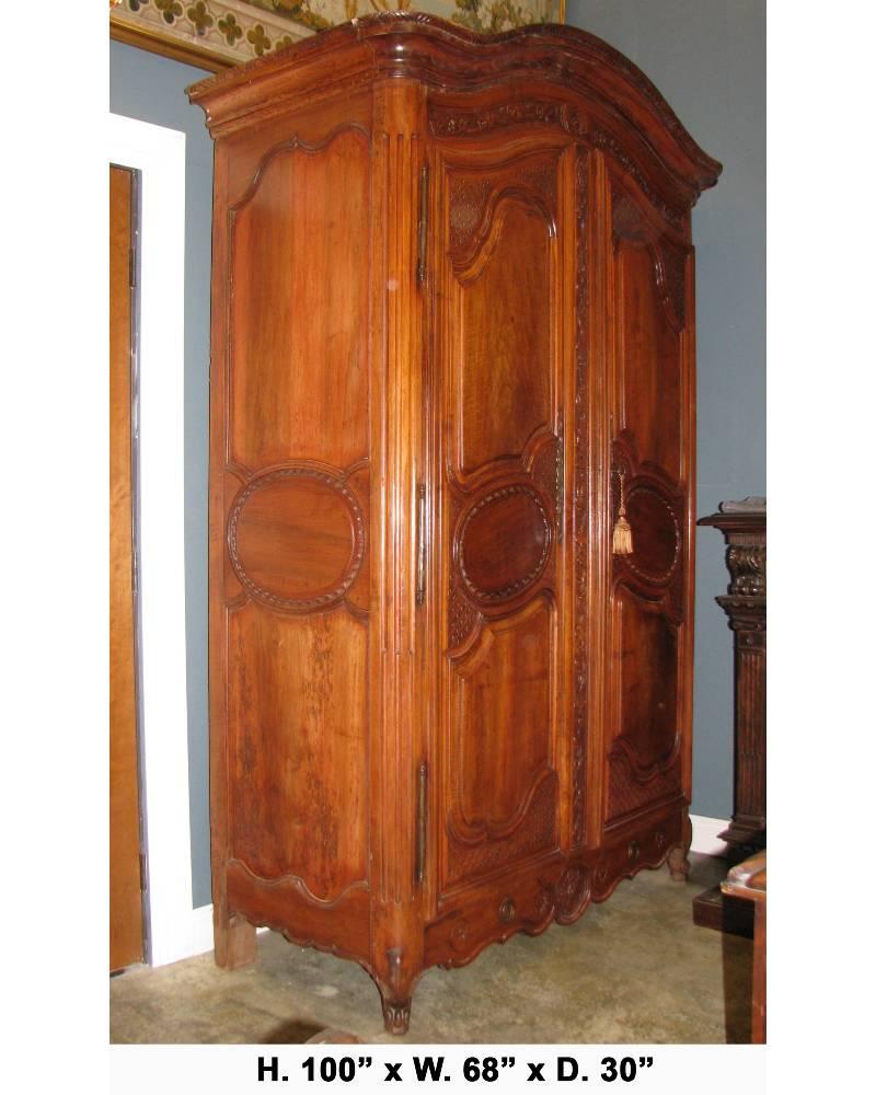 Extravagant and large 18th century French Louis XV finely carved walnut armoire with original hardware. The interior contains a shelf and two drawers.