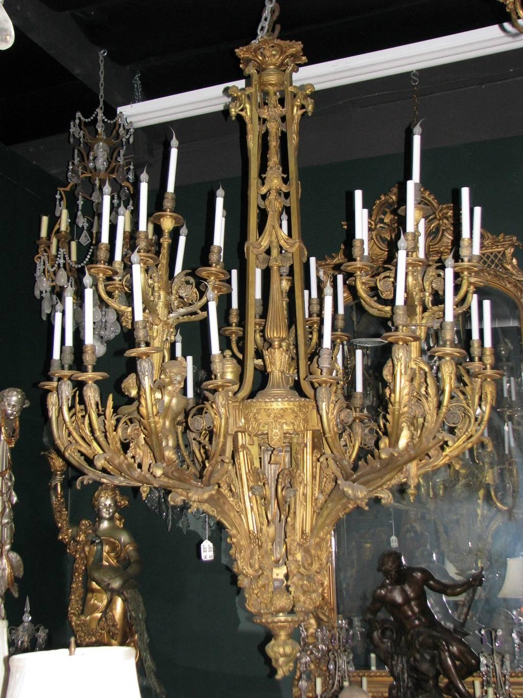 Extraordinary and enormous French Louis XV style bronze figural thirty-nine-light chandelier, 20th century. 
The top of the central shaft begins with three small angels holding floral urns located between three scrolling swags above three beautiful
