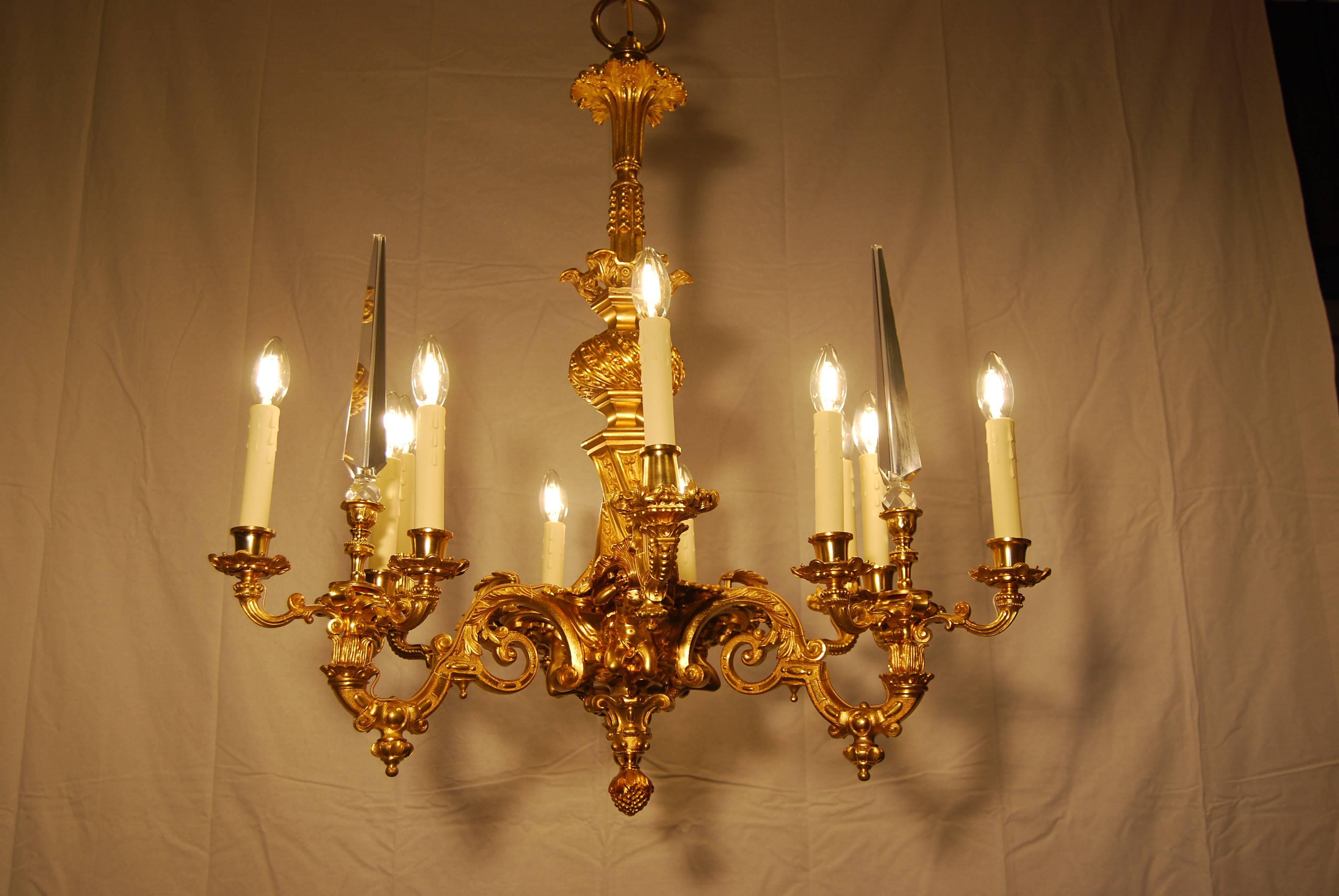 This is an unique twelve-light Ormolu Louis XV chandelier.
Three cherubs are holding the chandelier at the lower part.
Cast bronze and fire gilded ornaments.
Intended for candles and later converted to electricity.
Three crystal hand cut