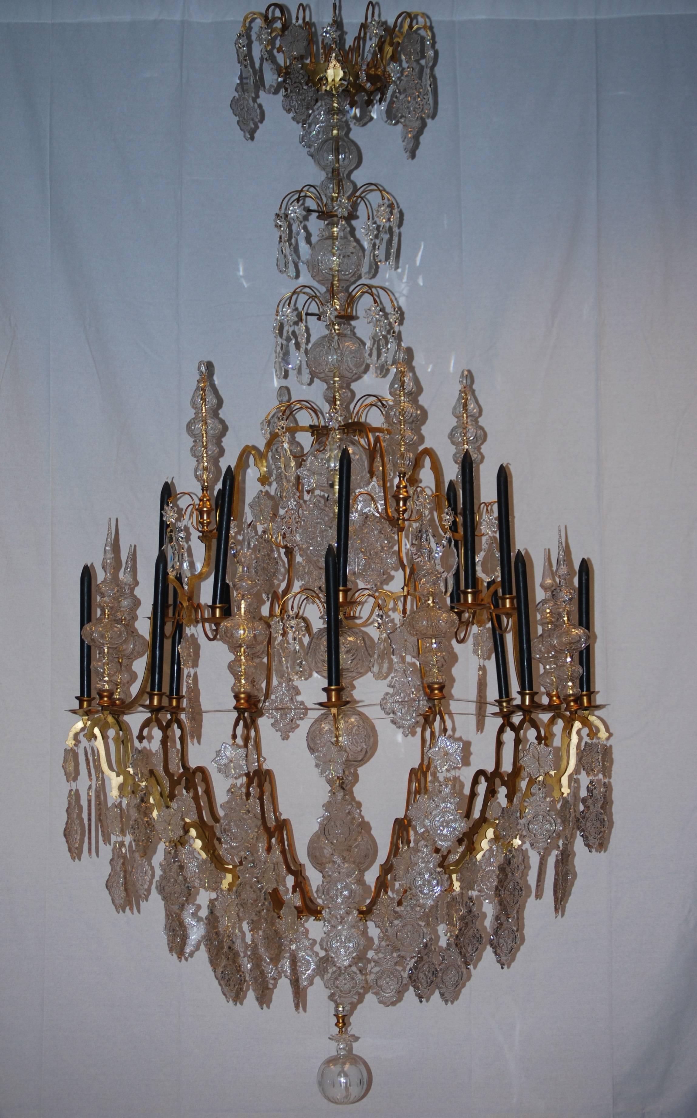 
An extremely large gilded and rock crystal cage chandelier having two rows of arms totaling 16 candles holders within its frame giving a total of 16 lights with finials on two levels of rock crystal finials from which sprays radiate and curve
