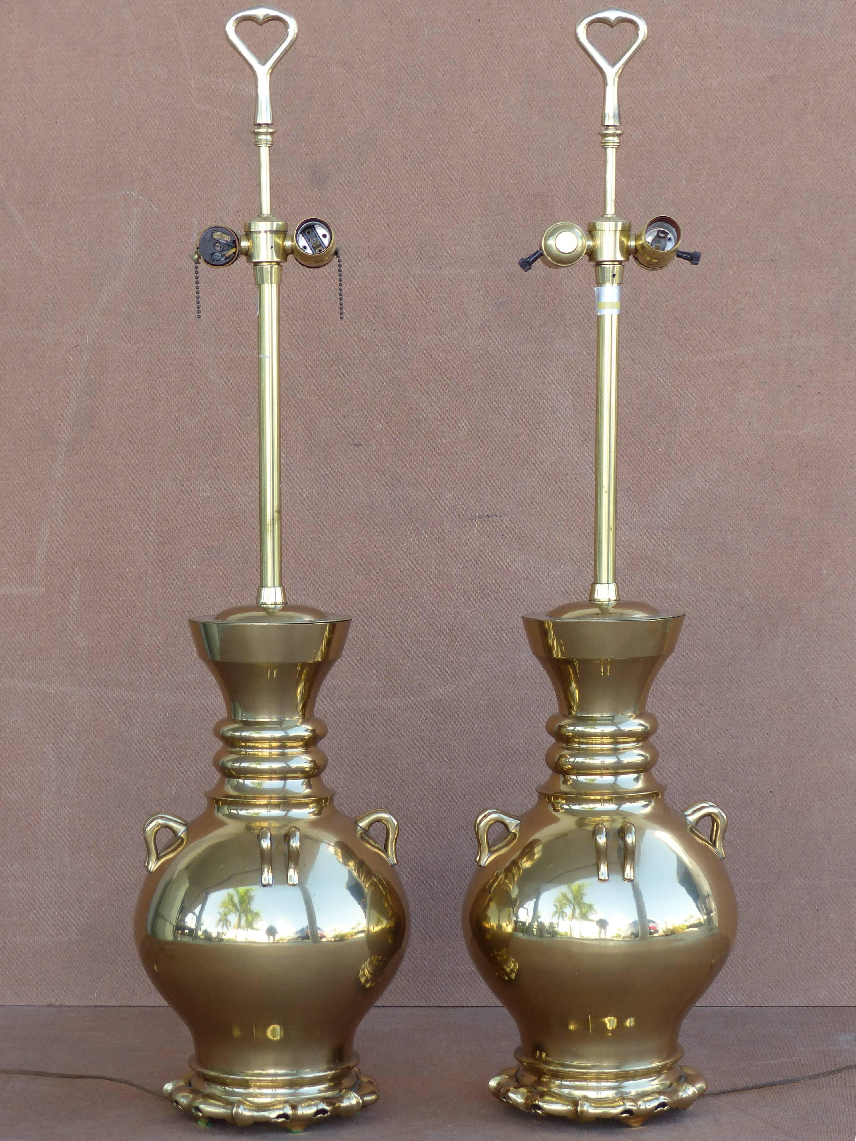 A fine quality pair of vintage brass lamps by Marbro. Shaped like urns with four handles, interesting jagged free-form bases, ribbed necks, and unusual finials that resemble bottle openers. Accommodate two standard socket bulbs. Original wiring in