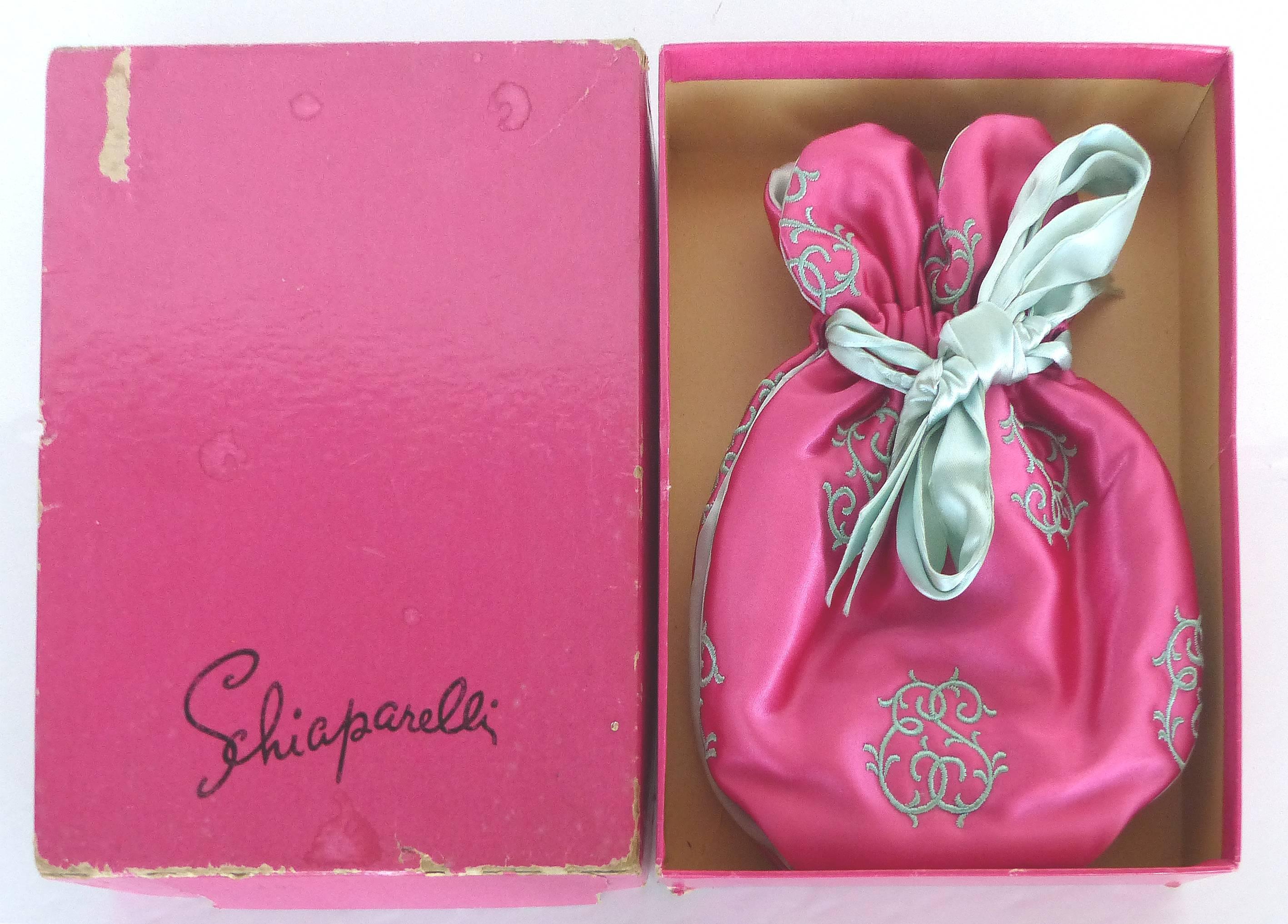 A rare 1950s embroidered satin boudoir jewelry ouch by Elsa Schiaparelli. The pouch secures with a contrasting ribbon and retains the original box. Measuring pouch, 7.5" L x 5.5" W x 1.5" D. 

  

  