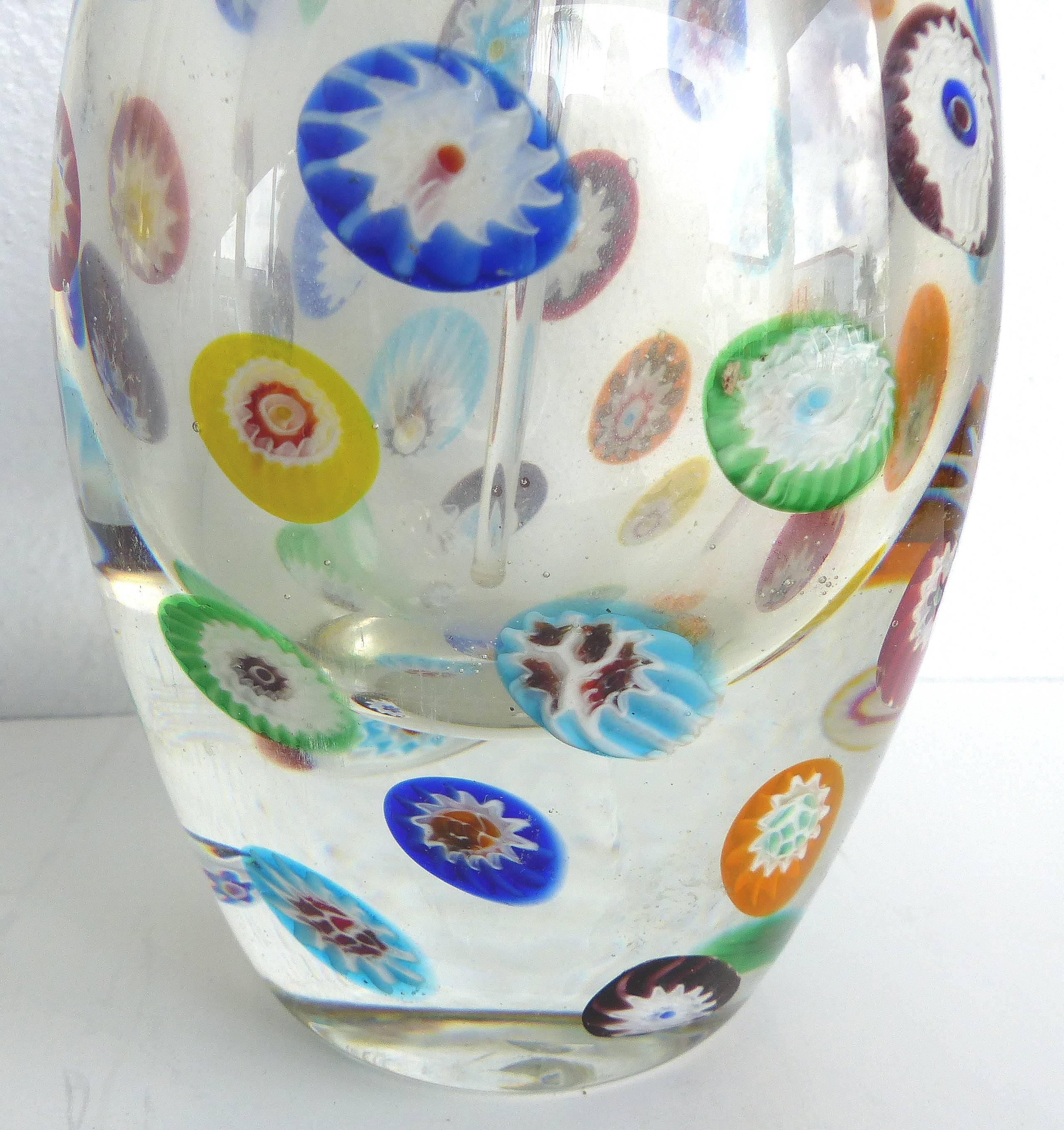 A large Murano Gambaro & Poggi colored Millefiori glass scent bottle with stopper. The vessel makes unusual use of Millefiori sparsely placed against a clear base. The bottle is topped with a large gold dusted ball stopper. The ground glass stopper