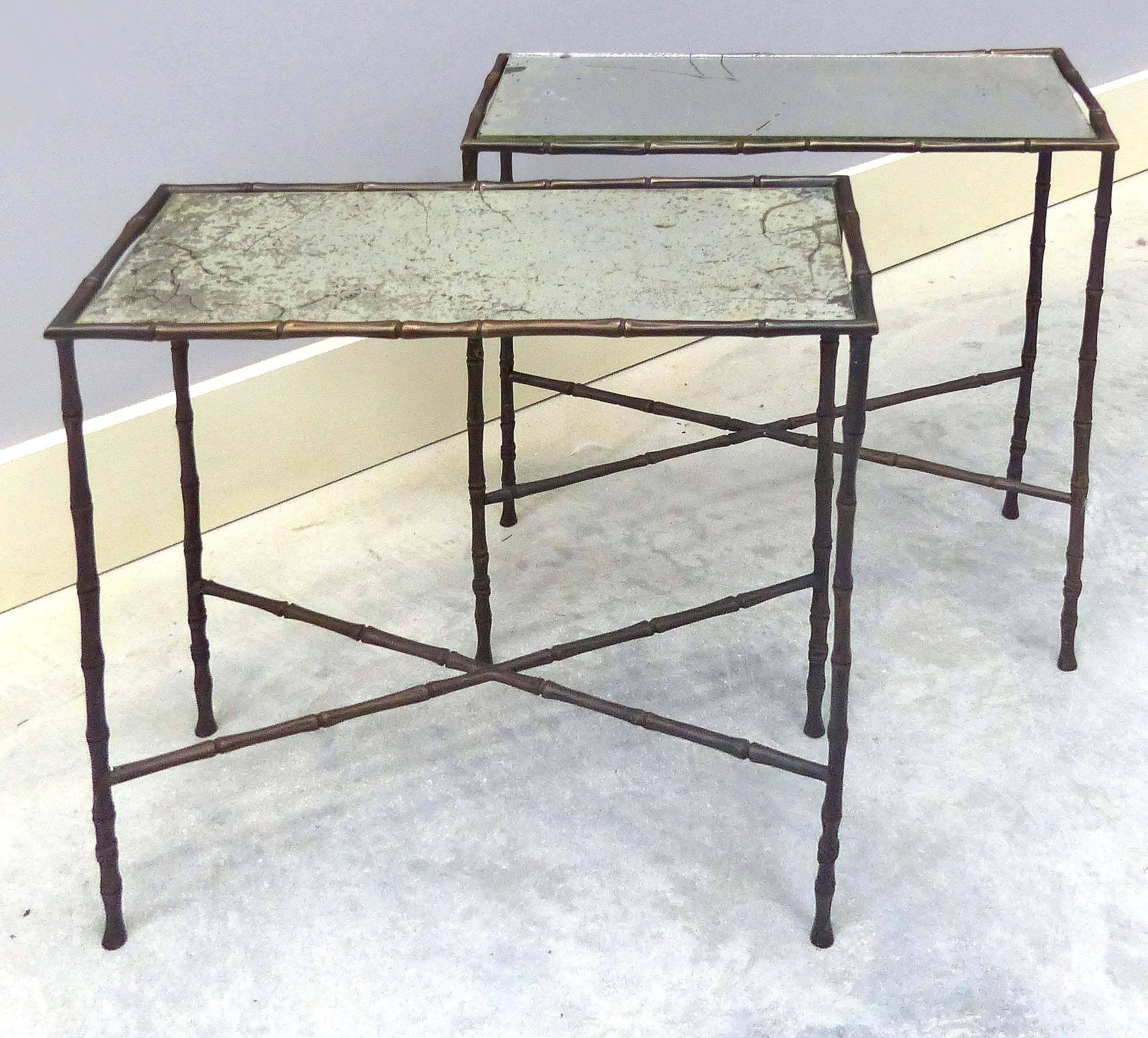 Offered for sale are a pair of Maison Jansen faux bamboo tables with aged mercury glass tops. Solid bronze frames are joined by crossed stretchers.