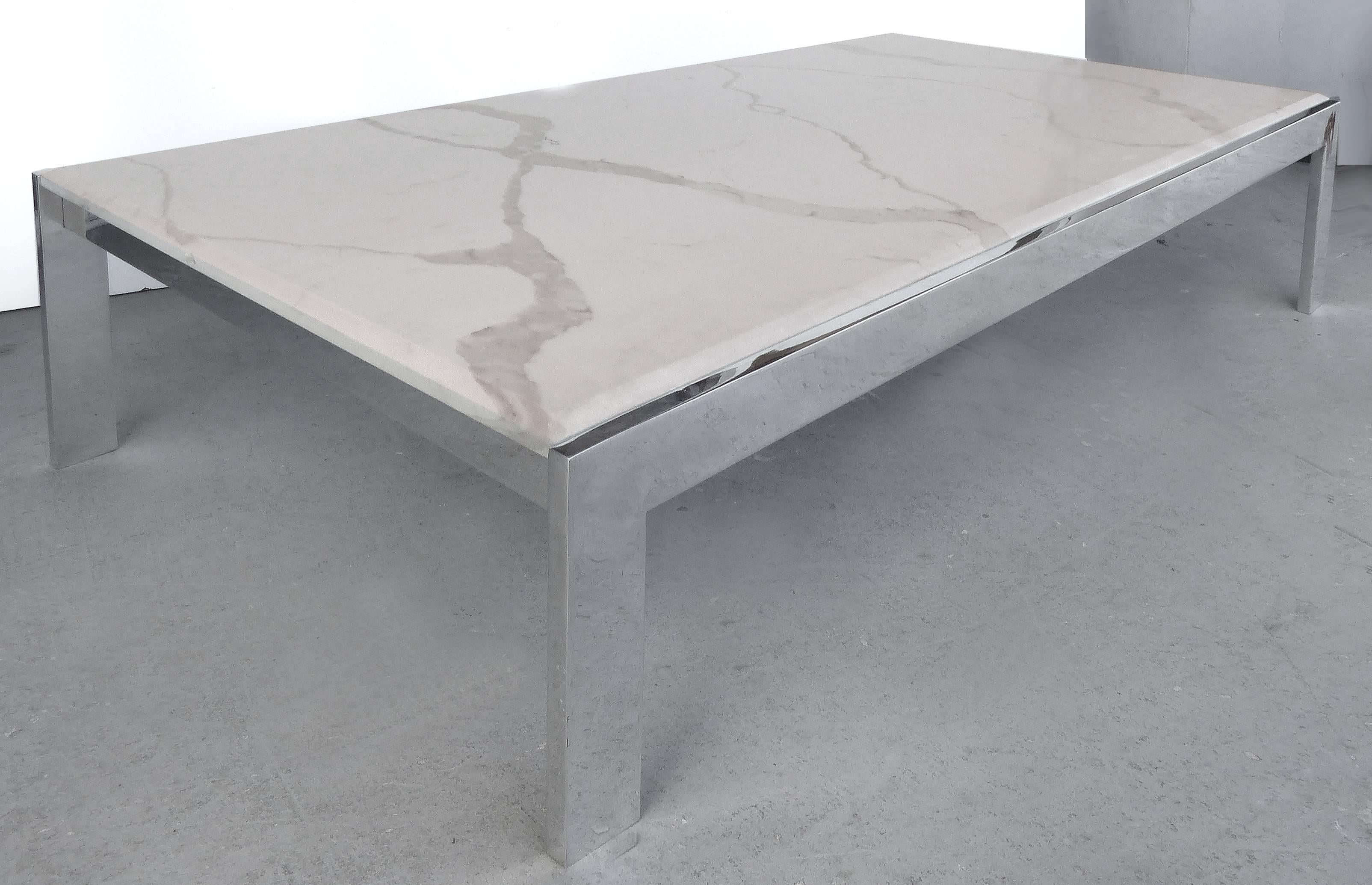 Offered for sale is a Minimalist coffee table with a solid polished aluminum base and a quartz top. The top shows a subtle gray veining pattern across the quartz. The ends of the top are beveled and extend beyond the frame.