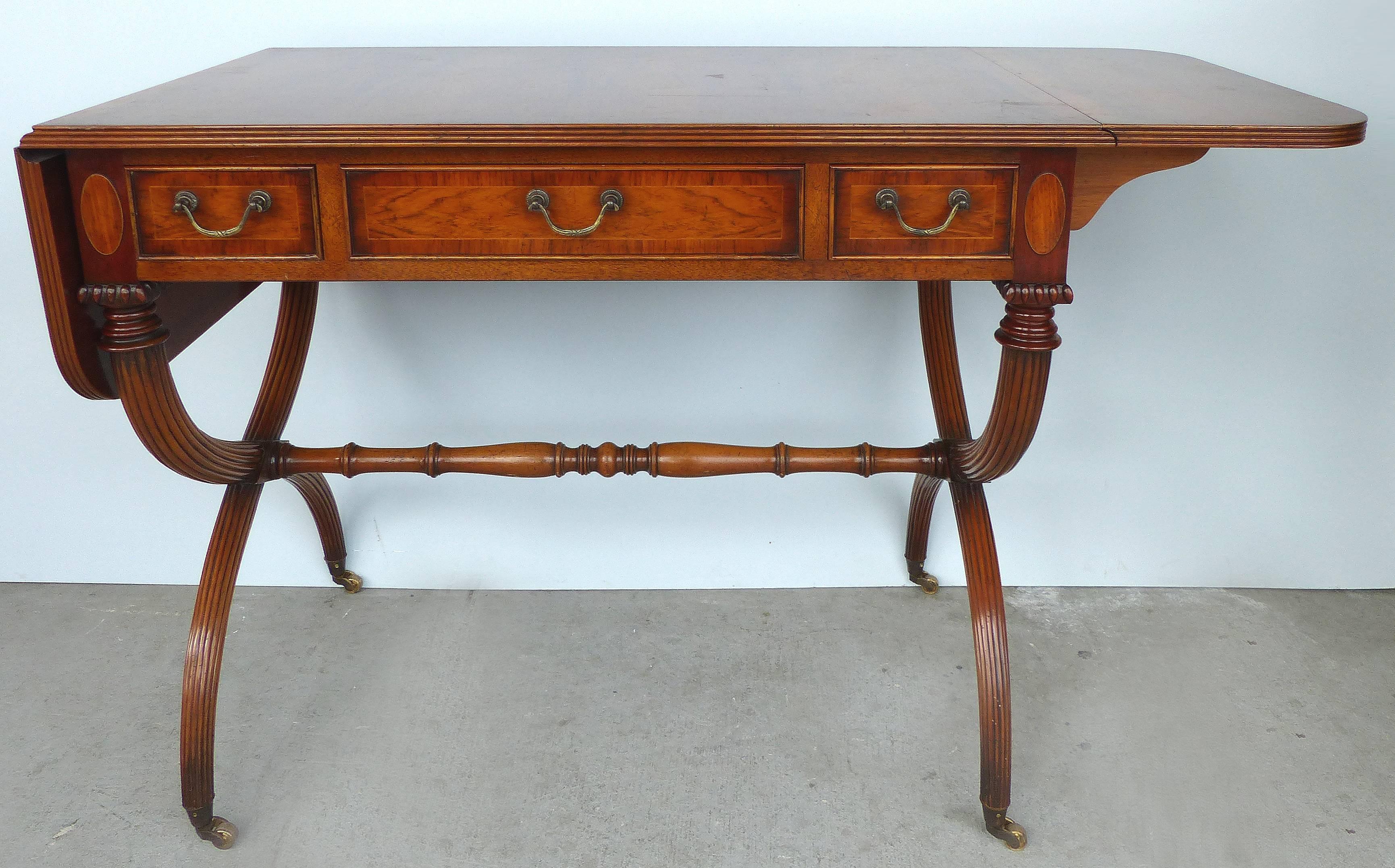 Offered for sale is a drop-leaf, hand-made Regency style server on casters by the E.G. Hudson Furniture Company of Sussex, England. The piece can also be used as a console table perhaps behind a sofa or as a ladies desk. The center has three slender