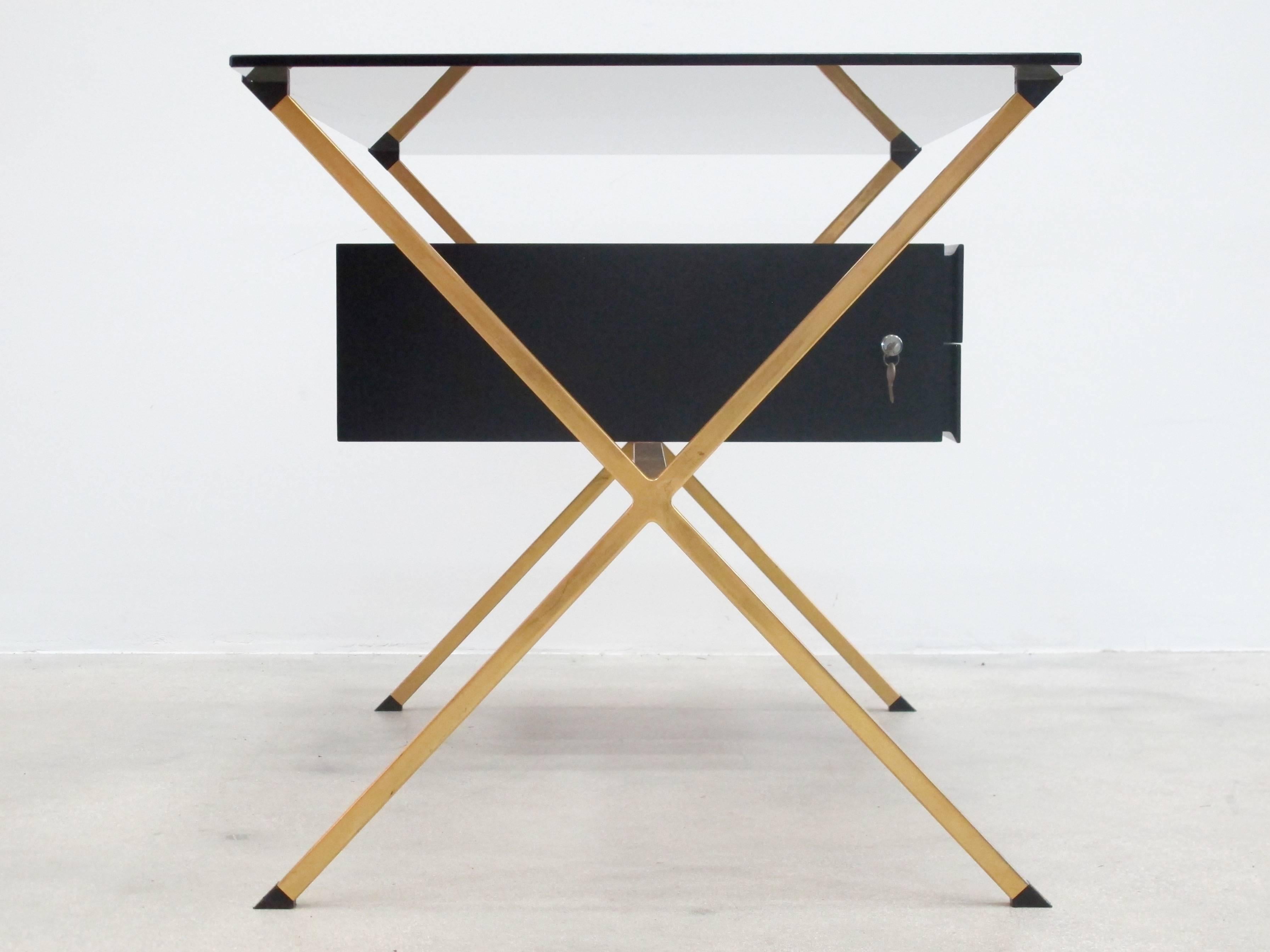 A rare Mid-Century Modern brass and smoked glass desk by the Italian designer Franco Albini for Knoll. Storage is provided beneath the glass top within an ebonized wood compartment with two locking drawers.