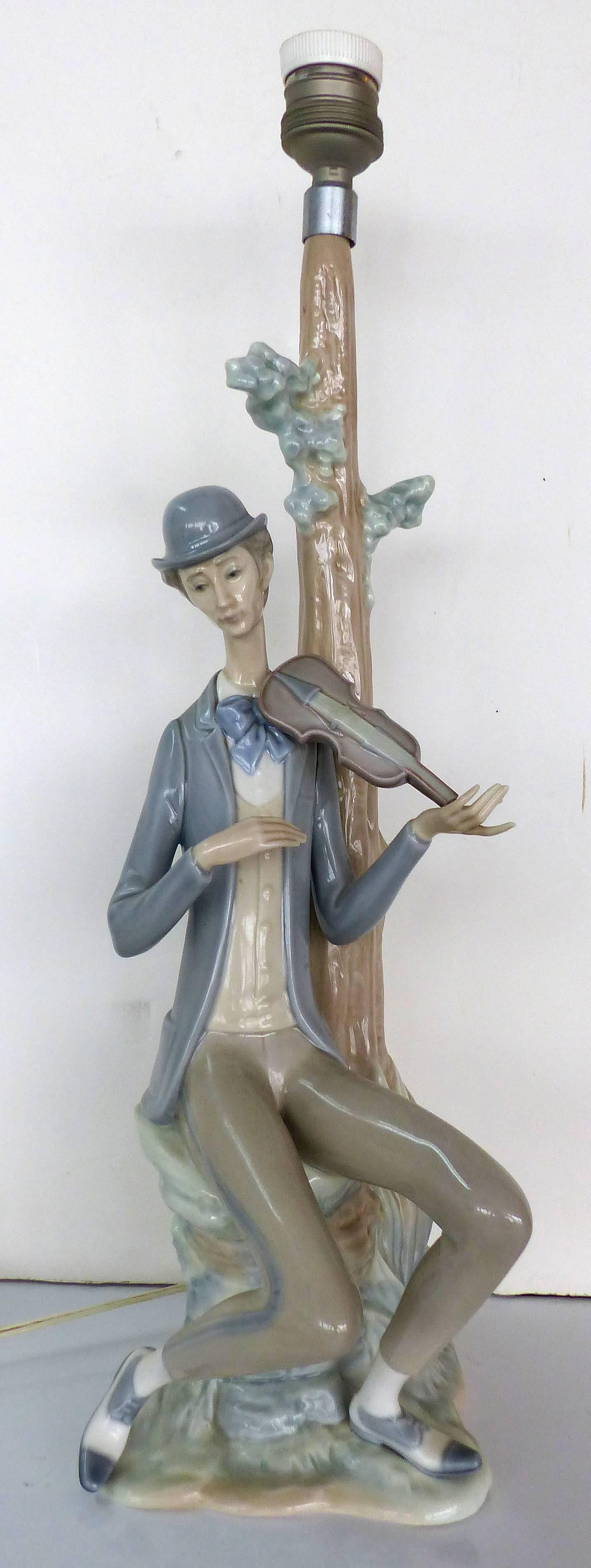 
A rare pair of table lamps by Vicente Martínez for Lladro. The boy playing a violin and the girl playing a mandolin are a matched pair and include the original Lladro shades. They are fully marked on the bases. The boy figure has losses to a