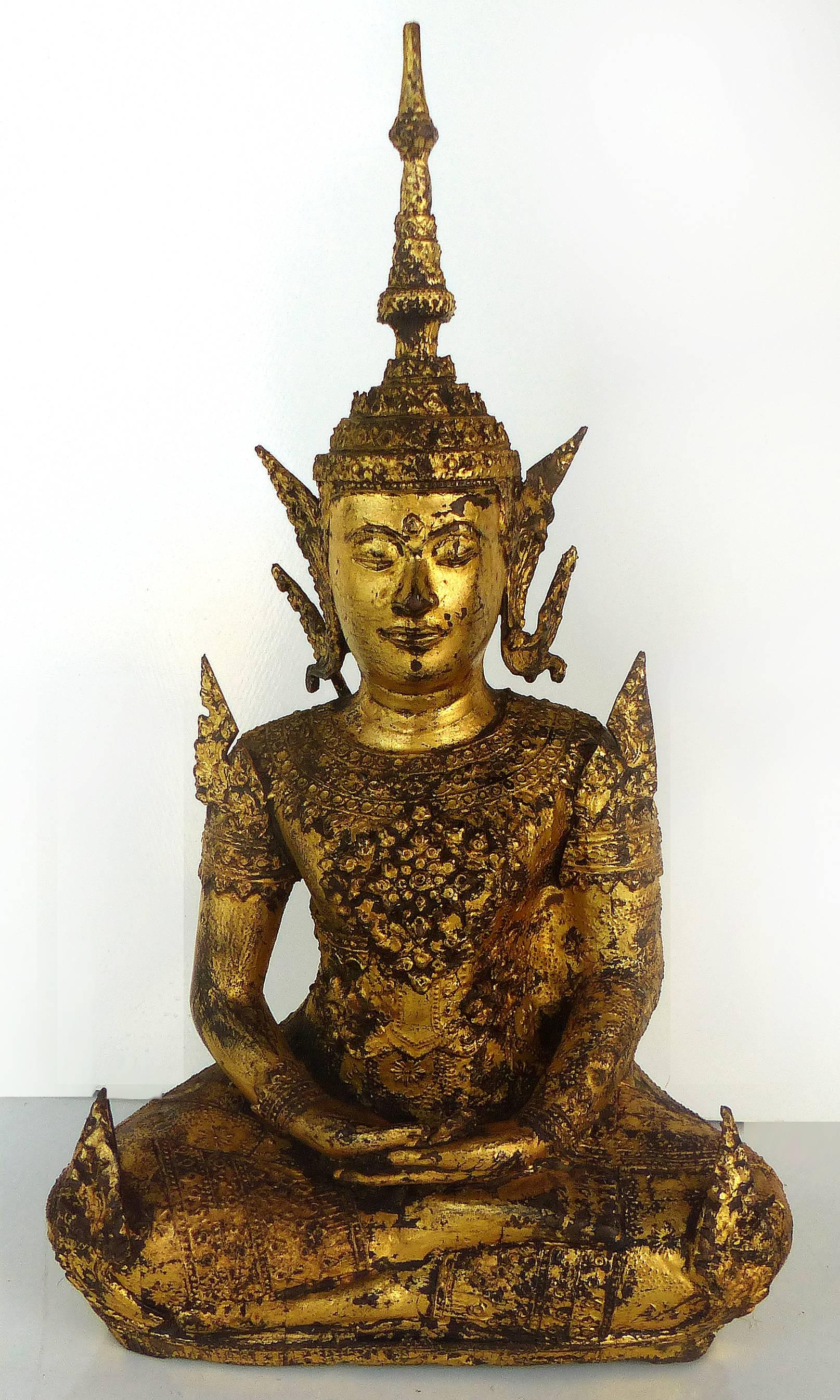 An antique bronze Buddha from Thailand with remnants of a gilt finish, circa late 19th century into early the 20th century, the Buddha is seated upon a modern fitted mahogany base.