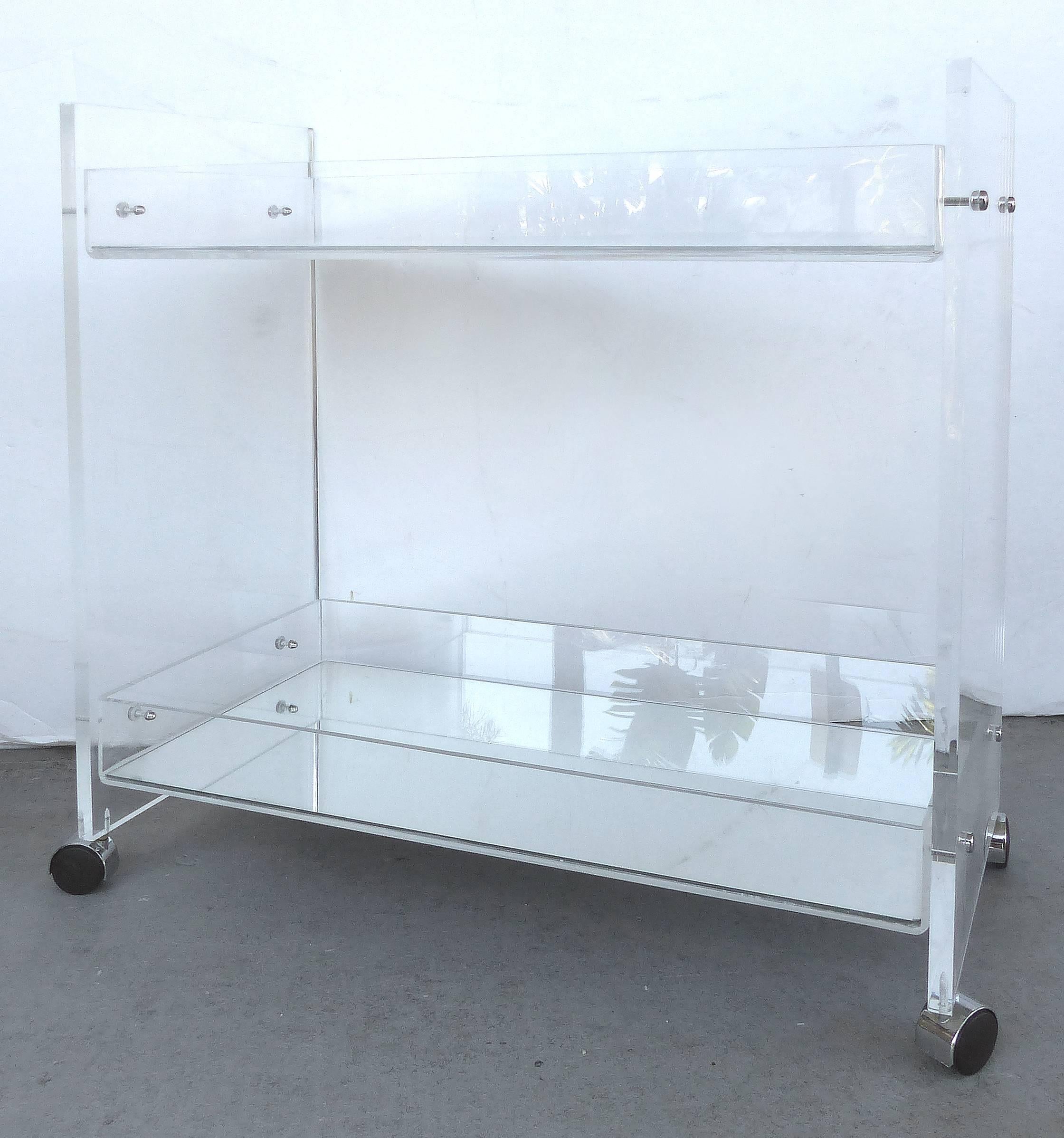 Bi-Level Rolling Lucite Bar Cart with Mirrored Serving Surfaces

Offered for sale is a Lucite bi-level bar cart with mirrored shelf surfaces. The cart or trolley rolls on casters and can be pushed from either end. The top work surface measures 25.5