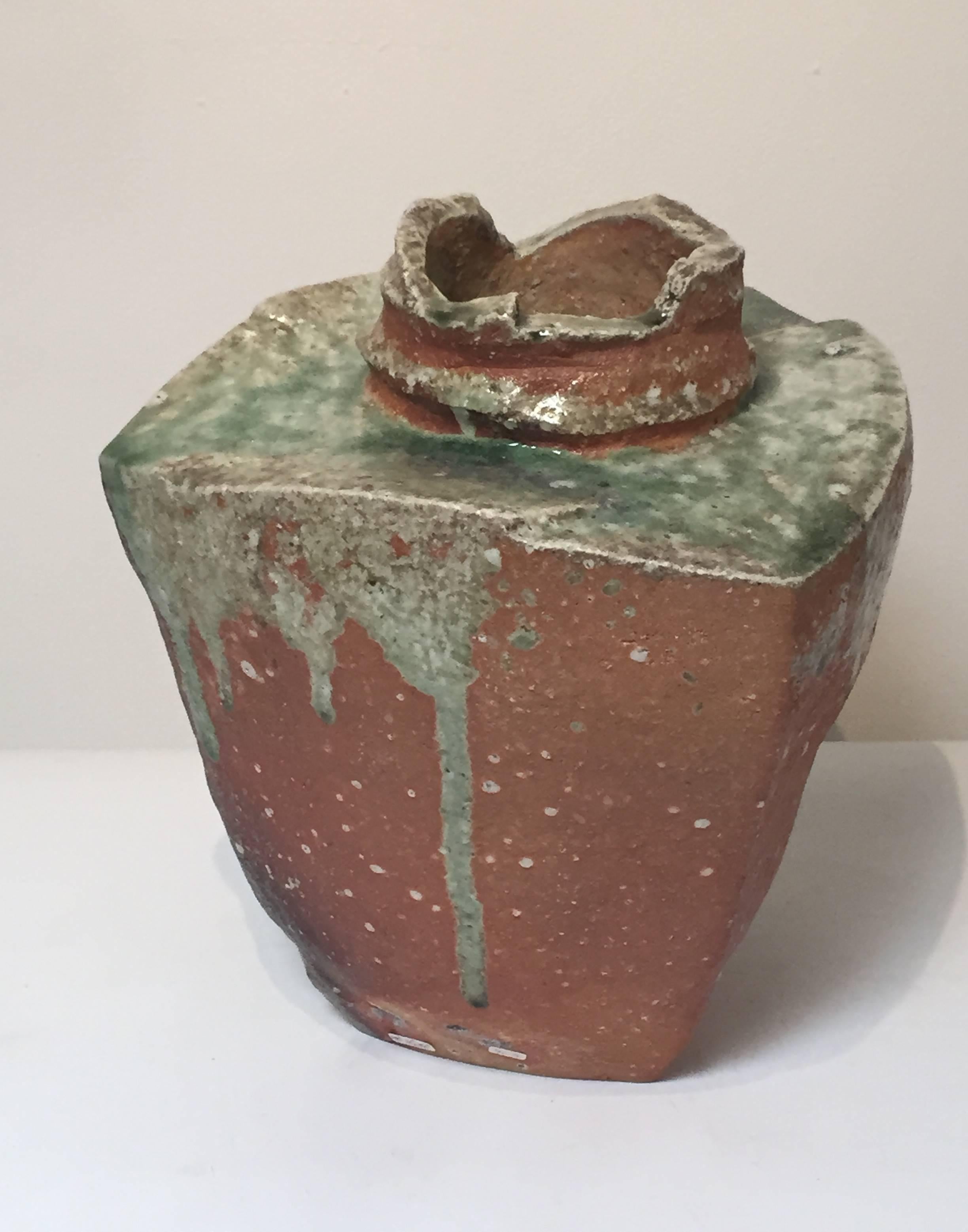 
Here is a stunning three sided vase in the Classic Iga Tradition of attaining spectacular ash glaze effects. Mossy green and emerald glazes POOL and drip over the burnt red clay.
Fujioka Shuhei is a master ceramic artist known for creating