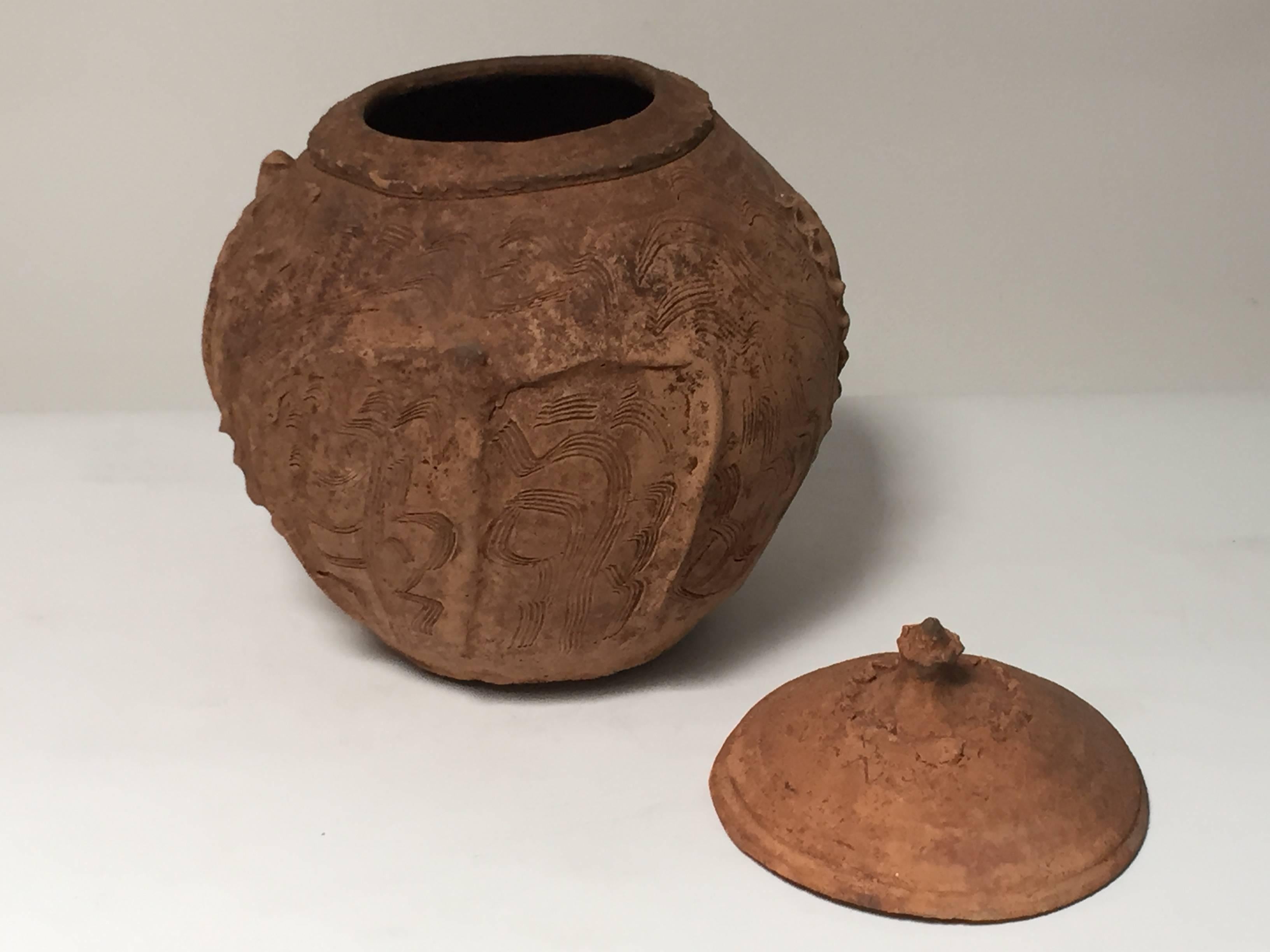 This ancient pottery vessel is decorated with four lotus shaped leafs that surround the jar. The clay body is orange and rust colored.
These vessels once held actual offerings, most likely food items.
 