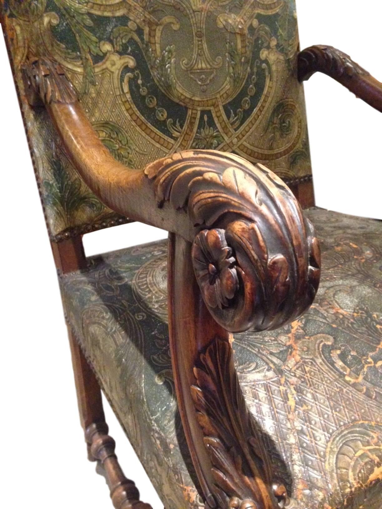 Ce fantastique fauteuil trône en noyer sculpté français du 19e siècle possède le cuir gaufré et peint d'origine datant des années 1870 et contient des garnitures en tête de clou. Les sculptures en bois le long des accoudoirs et des pieds sont