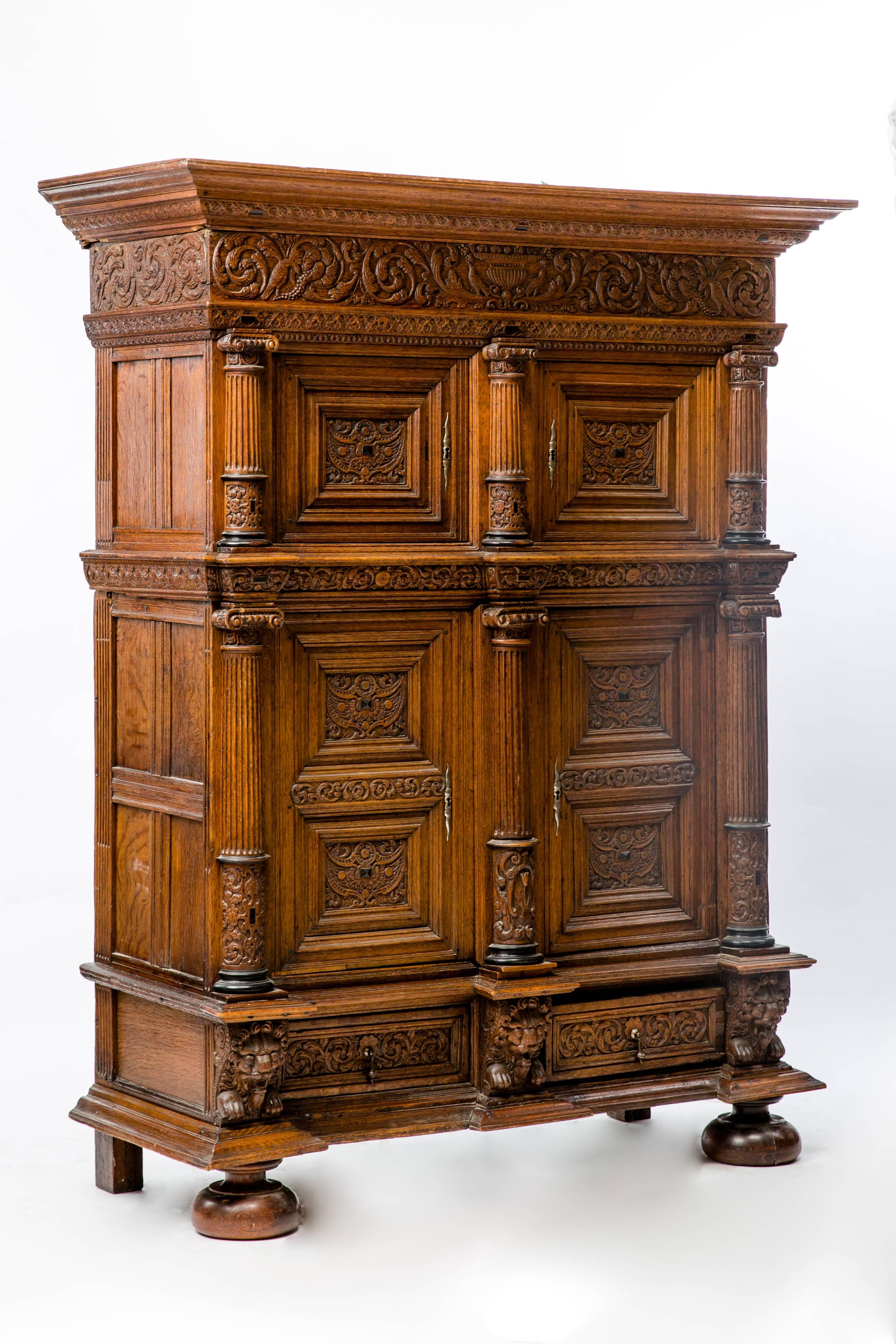 A 17th century oak, rosewood and ebonized cupboard with rectangular cornice moulding above a frieze drawer carved with overlapping roundels, flanked and divided by grotesques masks above a pair of paneled doors. These raised doors enclose a plain