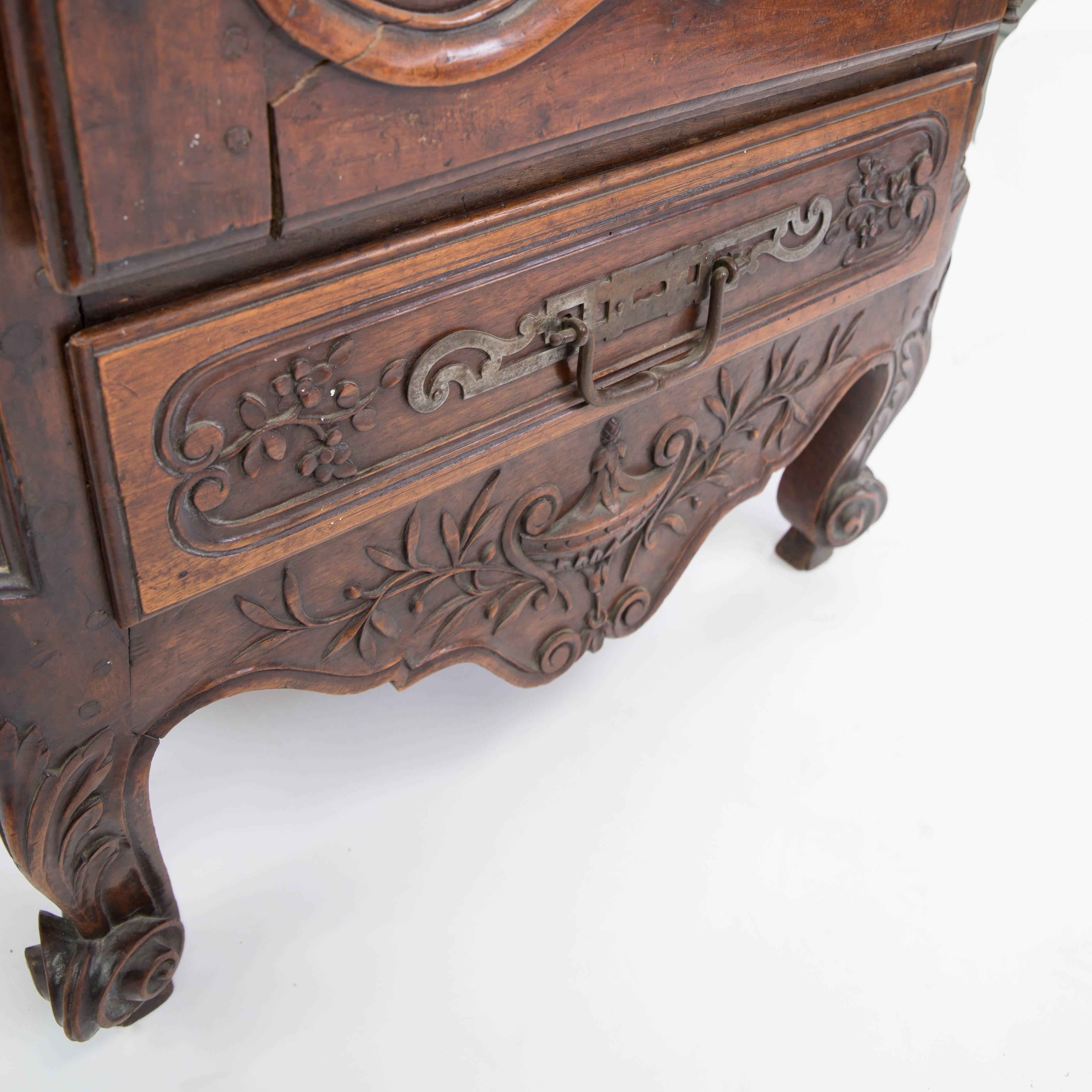 An extraordinarily tall mid-18th century Louis XV Provincial fruitwood narrow armoire/bonnetiere with a rectangular cornice. The frieze is centered by a basket of flowers, the wire mesh inset door is carved with laurel leaves, straw hat and