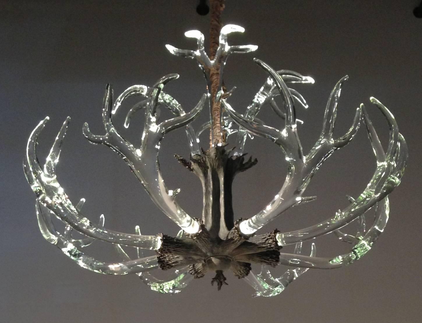 A very stylish interpretation of the traditional antler chandelier with a bronze center mount and solid hand-sculpted crystal antlers, by artist Jason Lawson.

The mount has LED lights within, which dramatically illuminate each antler.

Each