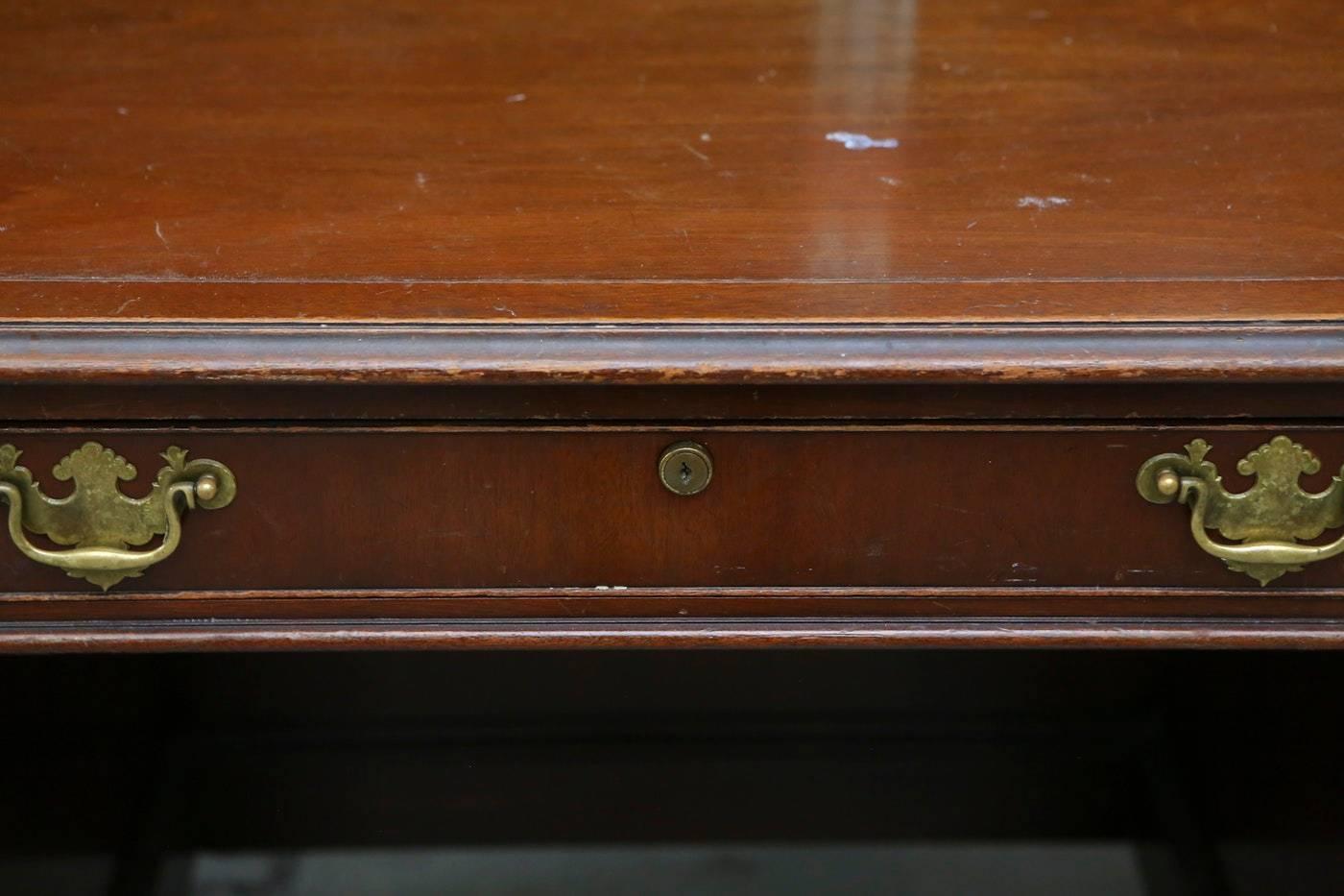 A Kittinger solid wood lawyer's desk. The desk is made of solid mahogany wood. The desk has a long thin drawer in the center flanked by four drawers to the sides. The desk has ornate brass hardware and is market Kittinger on the inside drawer.

In