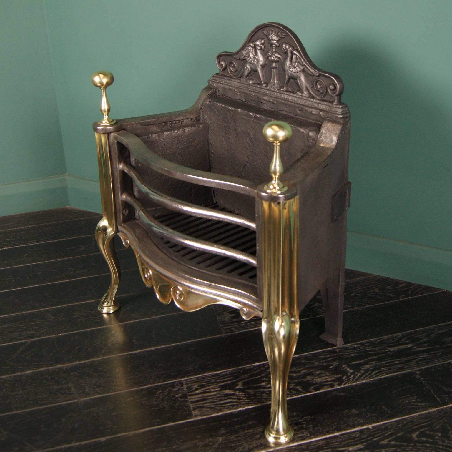 A cast-iron and brass fire basket (by Thomas Elsley of London), solid brass scrolled fret between shaped legs. Cast-iron shaped front bars with ball finials uppermost and an ornate crested back plate.