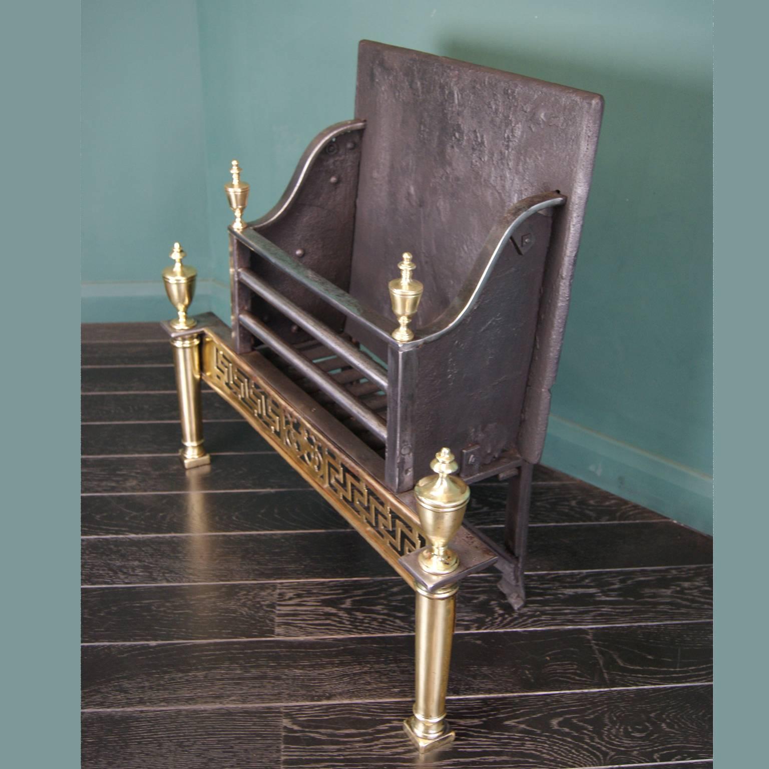 An elegant 19th century wrought and brass fire basket with plinth and column legs, a pierced Greek-key fret and urn finials uppermost. Rear elements include: Wrought iron grill and scrolled feet.