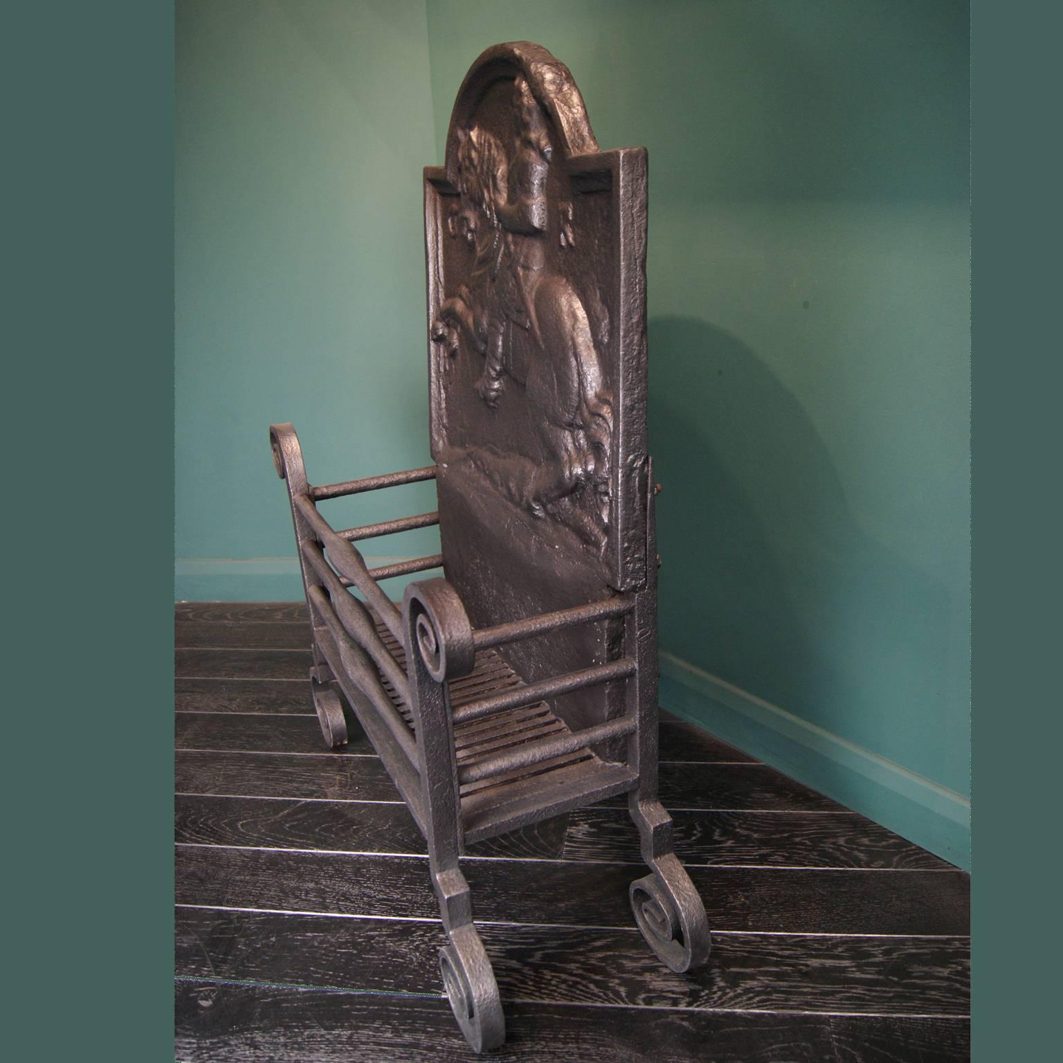 A large wrought fire basket, with shaped fire bars, scrolled feet and finials by Thomas Elsley. The ornate fire back depicts a horse and rider; finish in stove black and graphite wax.