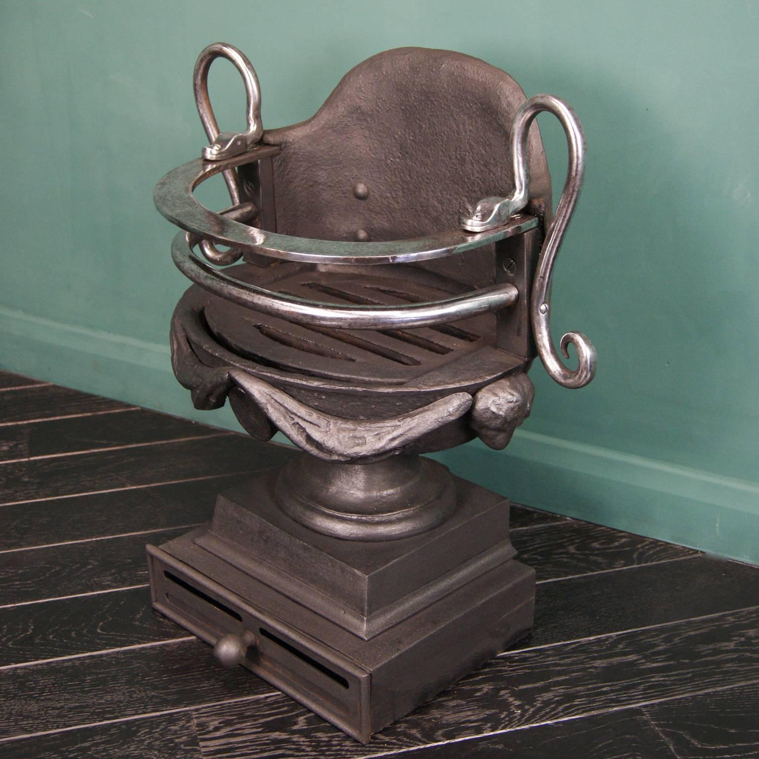 A Regency design polished wrought and cast-iron coal grate on plinth. This fire grate is flanked by looped serpents on polished wrought iron fire bars. The urn is adorned with swag, oval and ram's head detail, circa 1880.