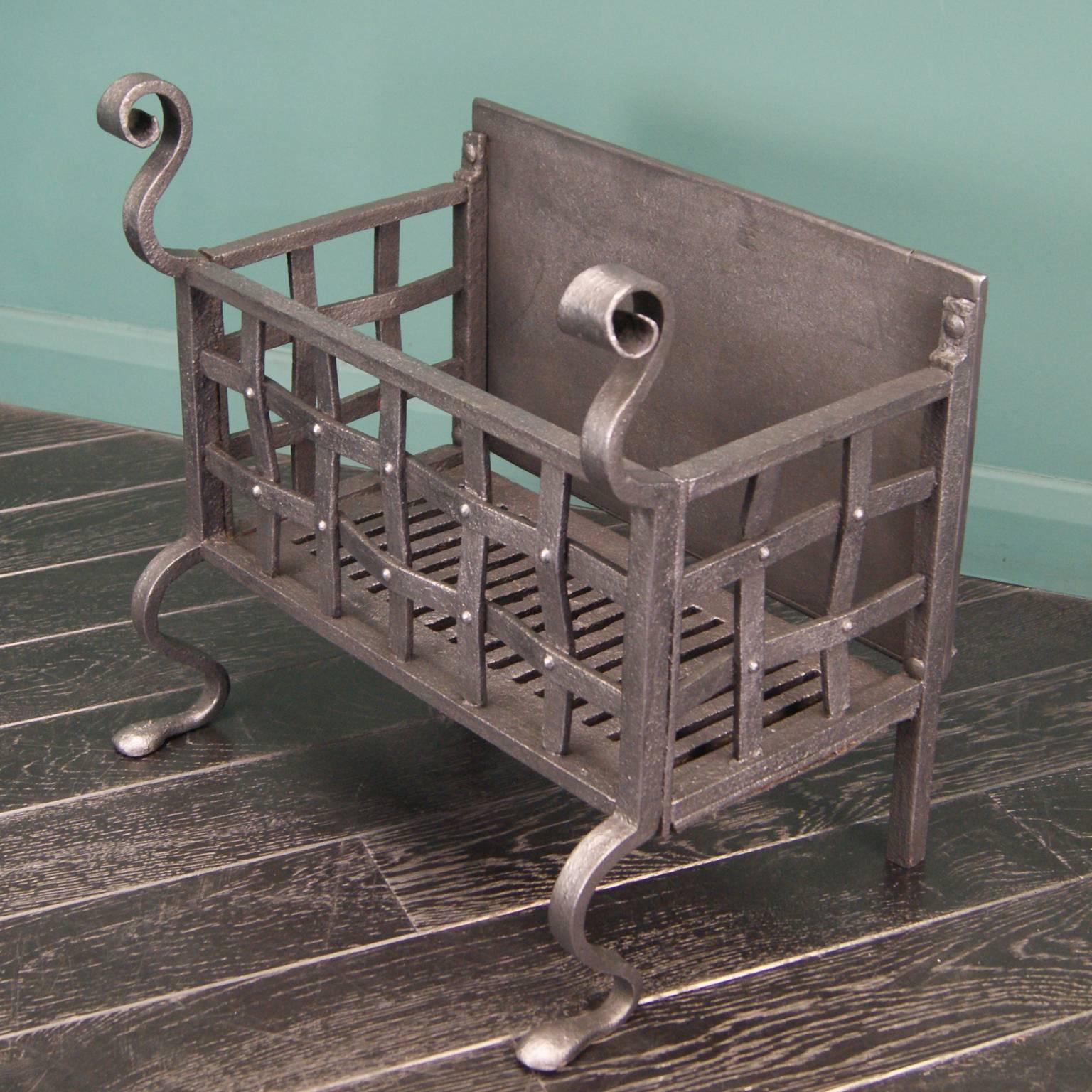 Wrought iron fire basket with shaped legs, scroll finials and rivet-work front,

circa 1890.